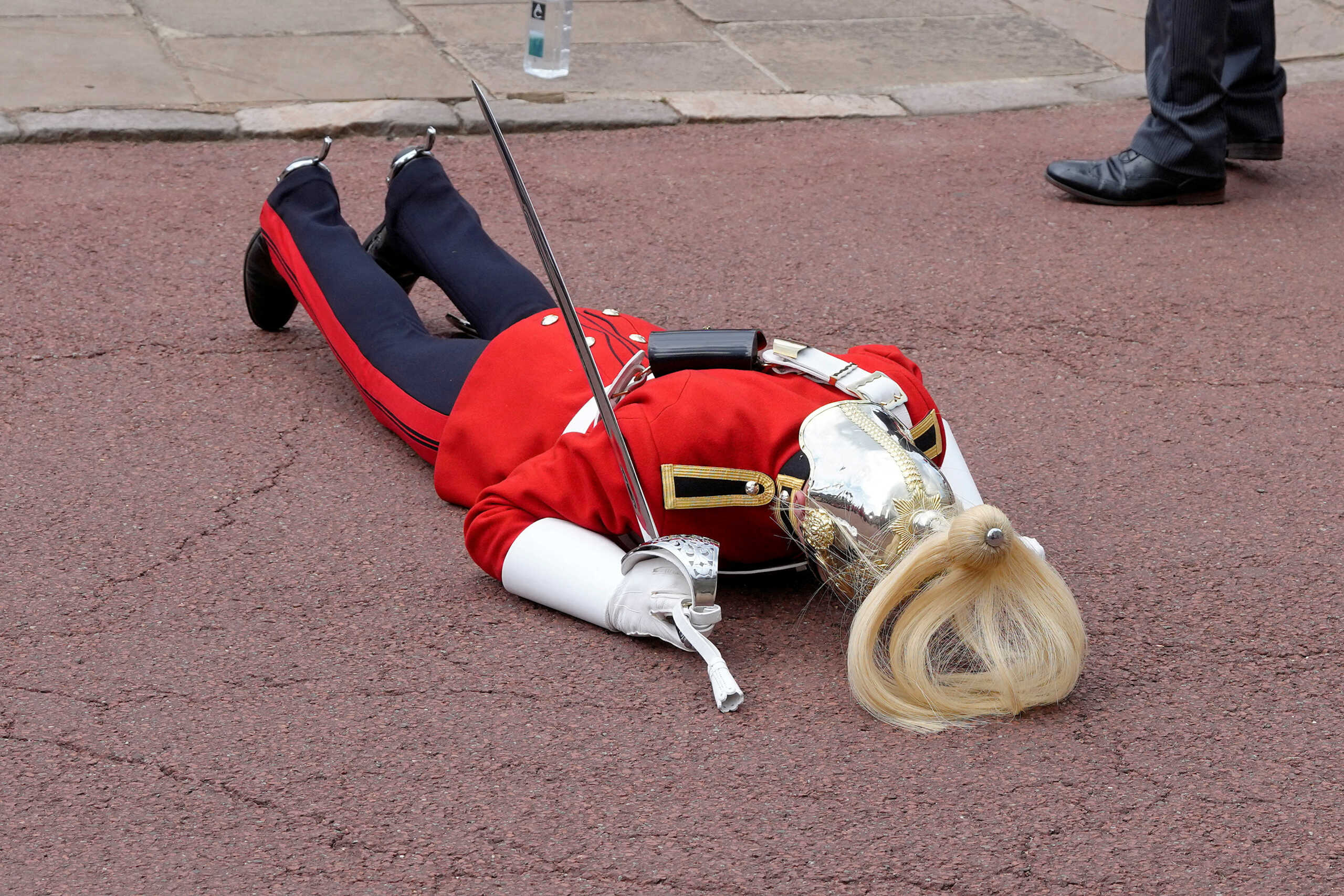 A soldier faints in the heat ahead of the Order of the Garter service at Windsor Castle, in Windsor, England, Monday, June 19, 2023.  Kirsty Wigglesworth