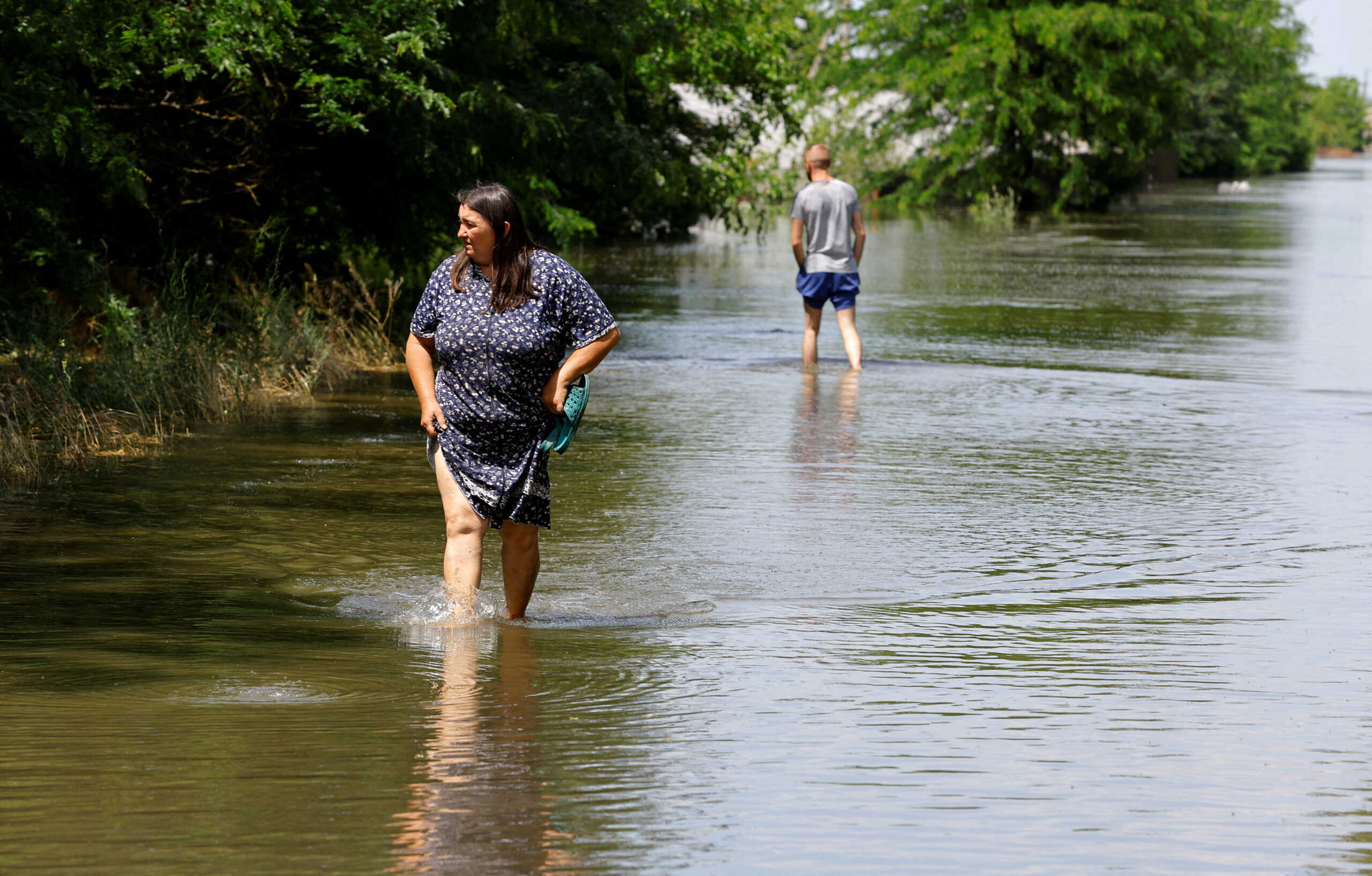 FILE PHOTO: People walk along a flooded road, that submerged in water following the collapse of the Nova Kakhovka dam in the course of Russia-Ukraine conflict, in the settlement of Korsunka in the Kherson region, Russian-controlled Ukraine, June 7, 2023. REUTERS