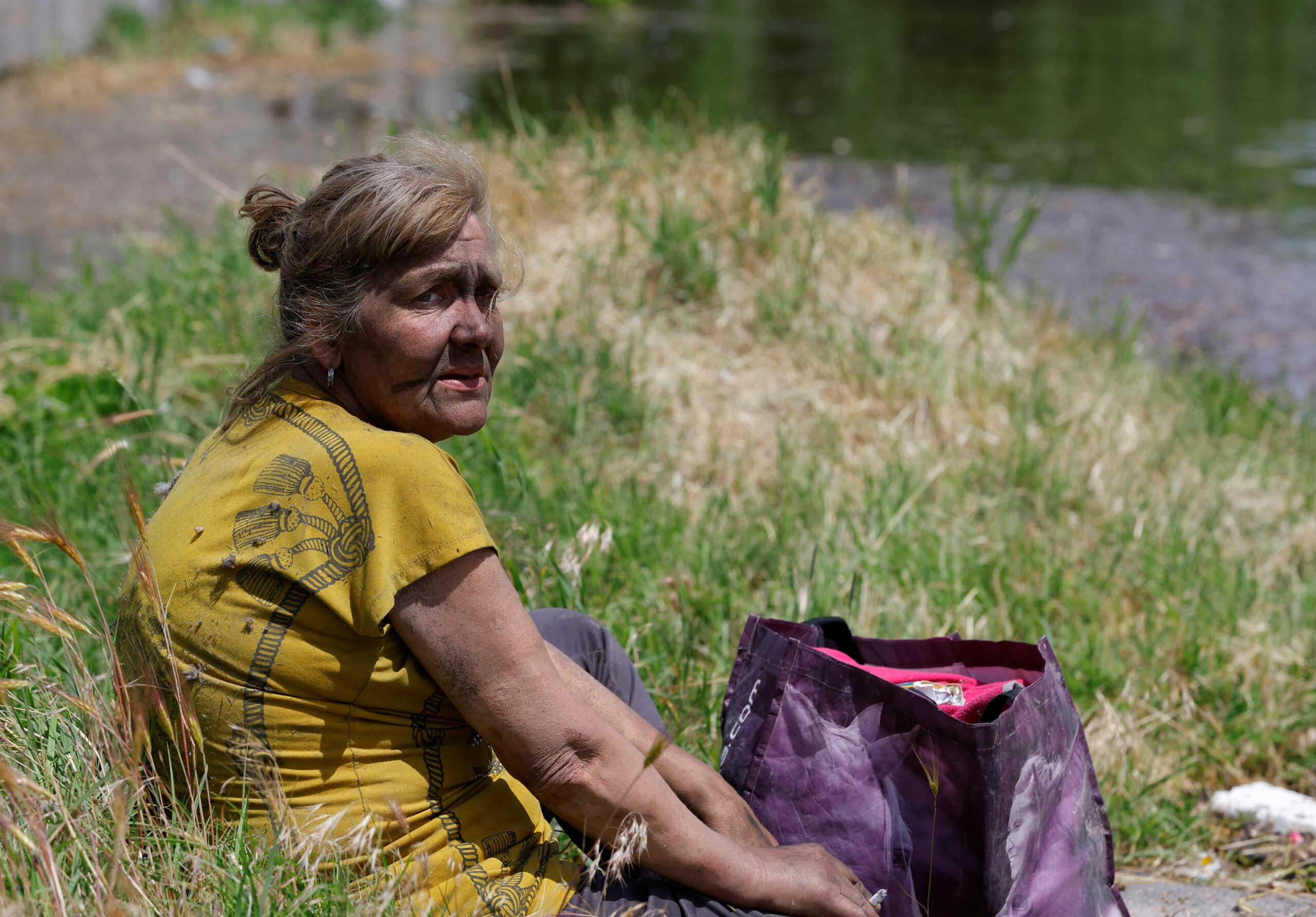 Local resident Valentina, who spent two days on the roof of a flooded house, sits on the ground after being evacuated to a non-flooded area following the collapse of the Nova Kakhovka dam in the course of Russia-Ukraine conflict, in the town of Hola Prystan in the Kherson region, Russian-controlled Ukraine, June 8, 2023. REUTERS