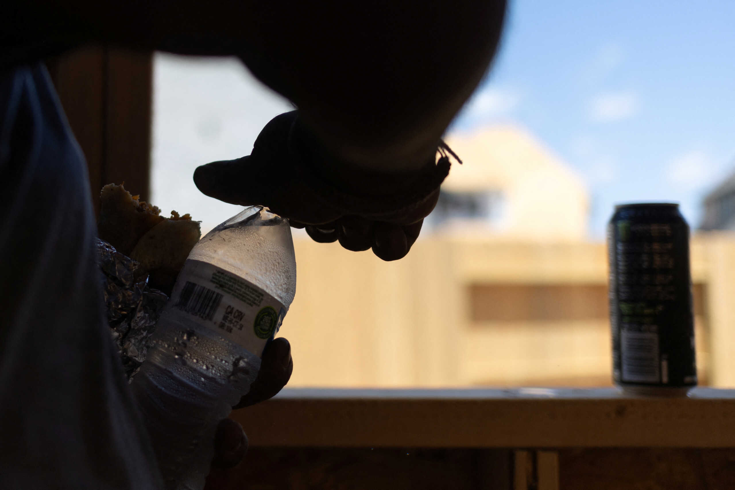 Luis Hernandez, a home builder from Mexico, opens a bottle of water during hot weather in Manvel, Texas, U.S., July 13, 2023.  REUTERS