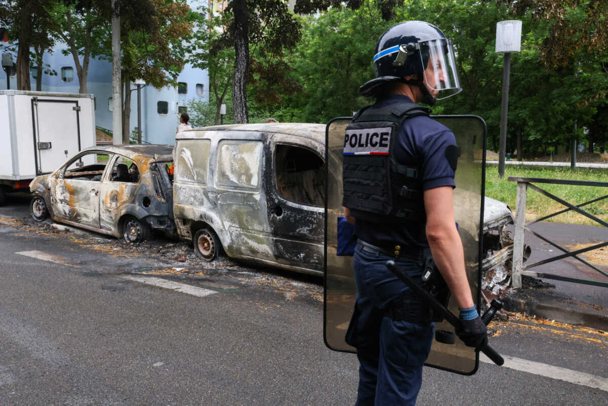 A French police officer stands guard next to vehicles burnt during a night of clashes between protesters and police, following the death of a 17-year-old teenager killed by a French police officer during a traffic stop, in Nanterre, Paris suburb, France, July 1, 2023. REUTERS