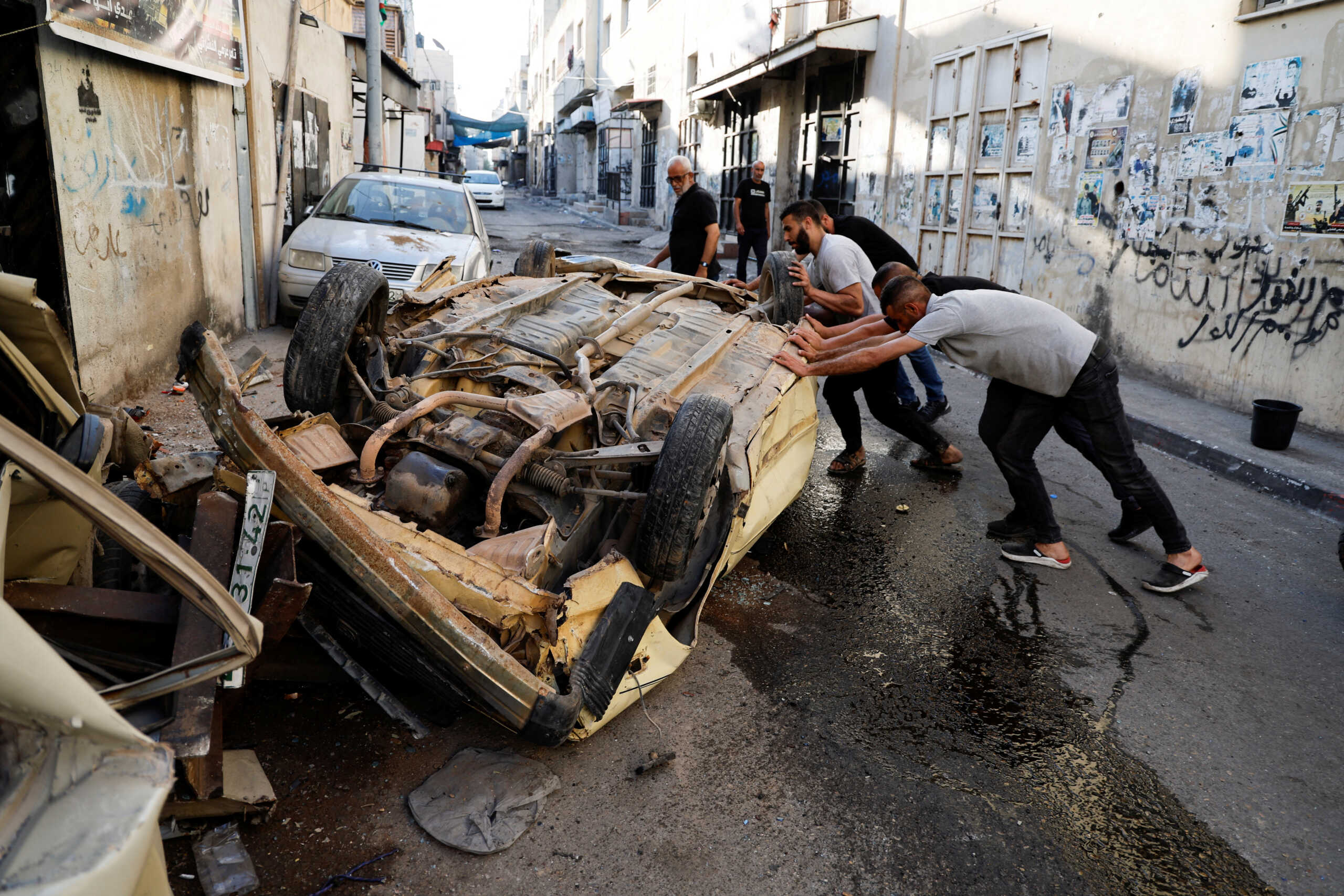 Palestinians try to move a damaged car after the Israeli army's withdrawal from the Jenin camp, in Jenin, in the Israeli-occupied West Bank July 5, 2023. REUTERS