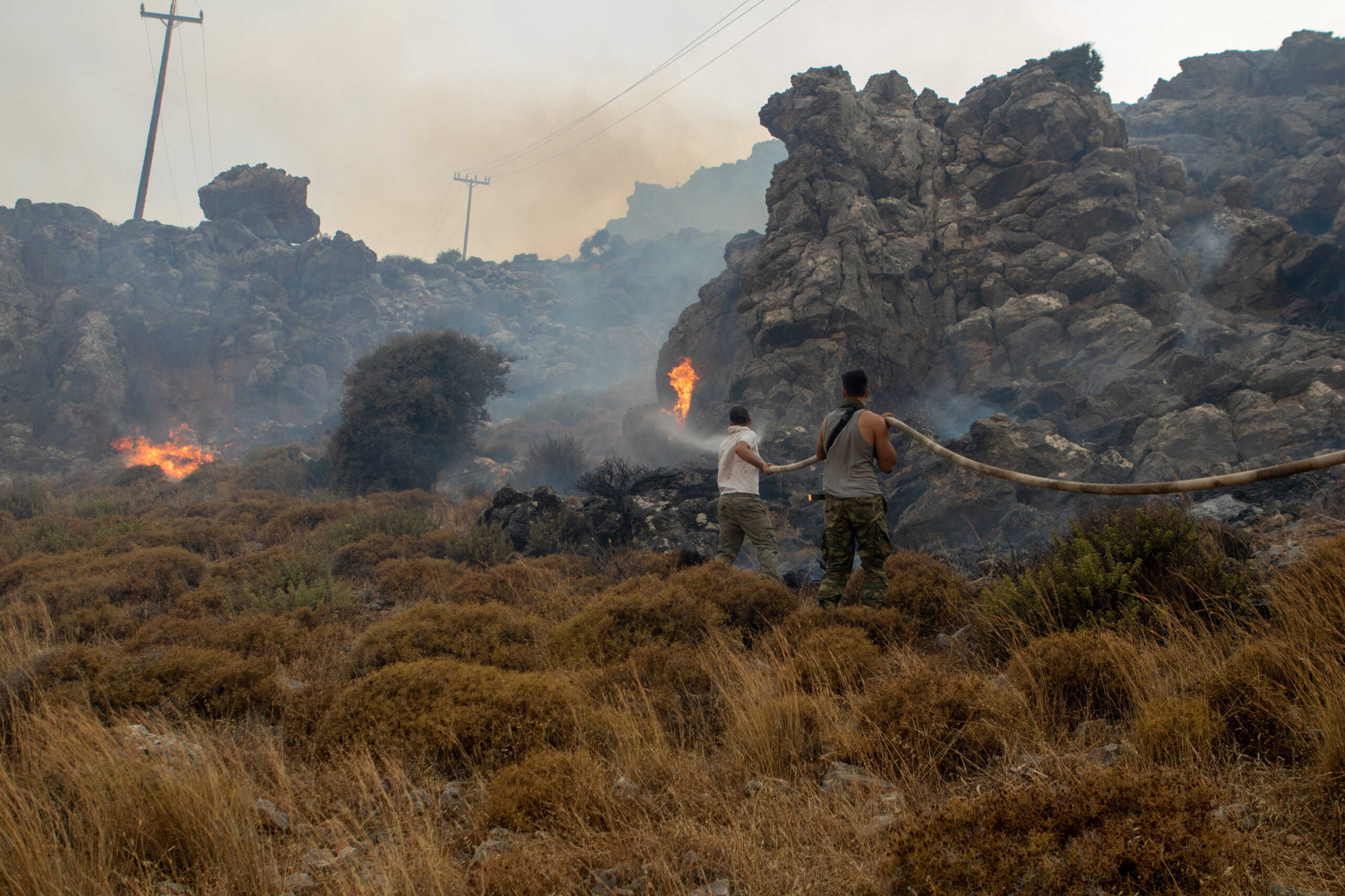 People try to extinguish a wildfire burning near Lindos, on the island of Rhodes, Greece, July 22, 2023. REUTERS