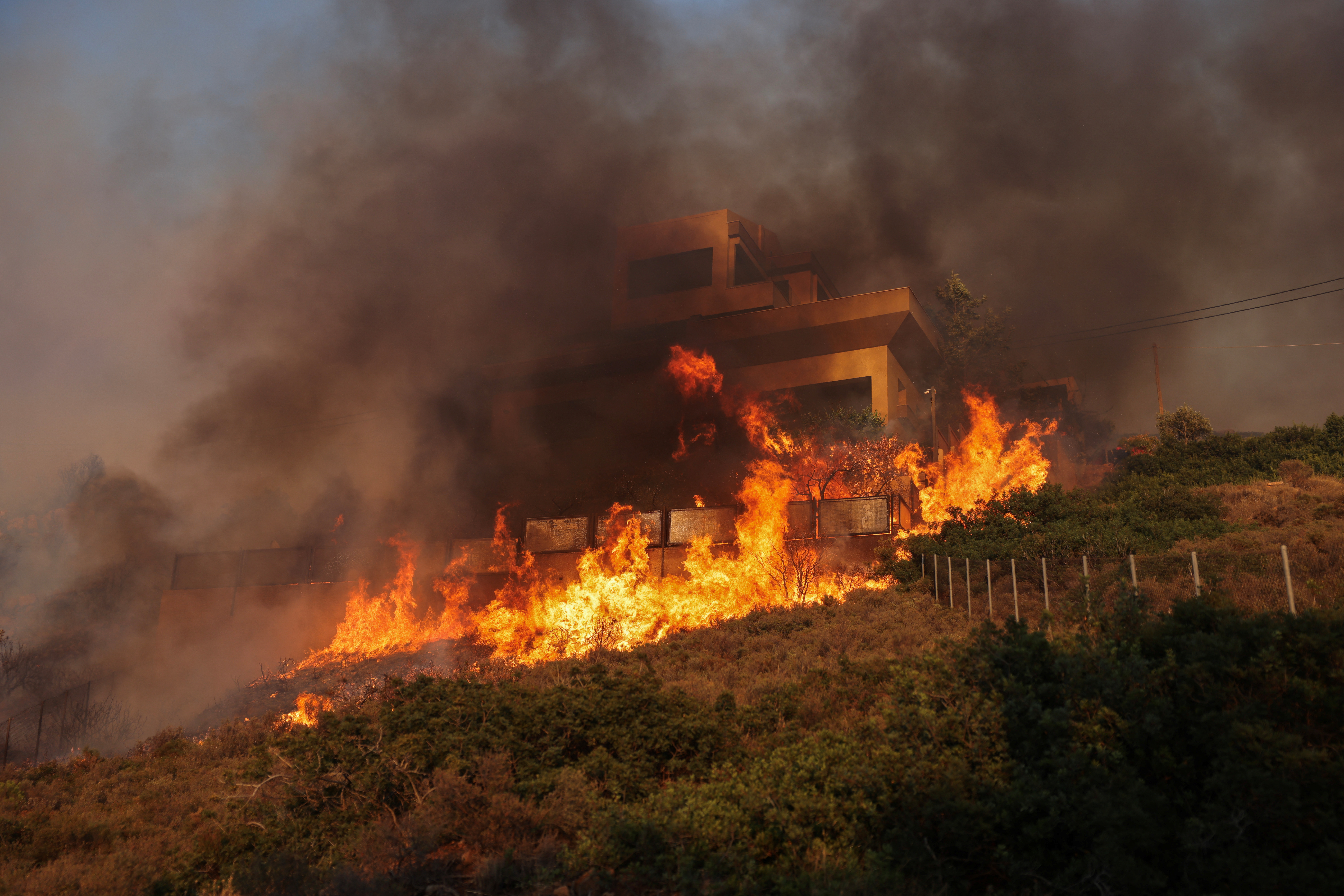 Flames engulf a house as a wildfire burns in Saronida, near Athens, Greece, July 17, 2023. REUTERS