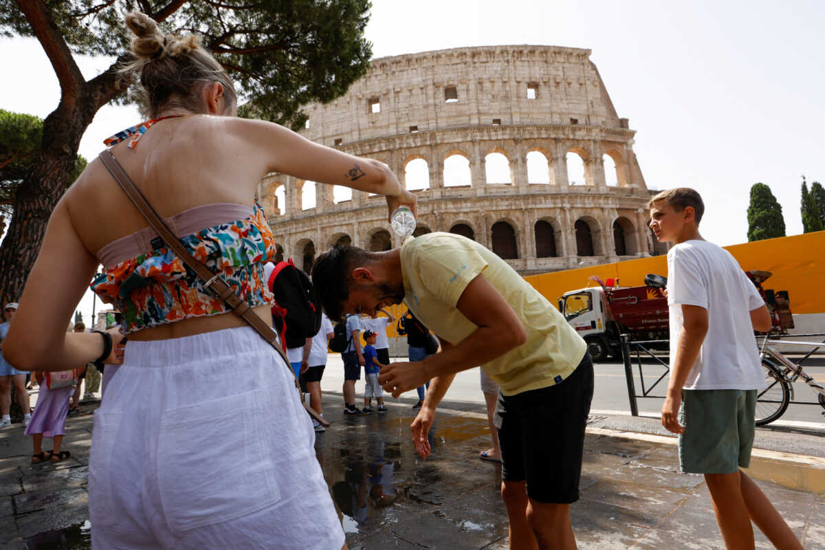 A woman pours water on a man near the Colosseum, during a heatwave across Italy, as temperatures are expected to rise further in the coming days, in Rome, Italy July 18, 2023. REUTERS