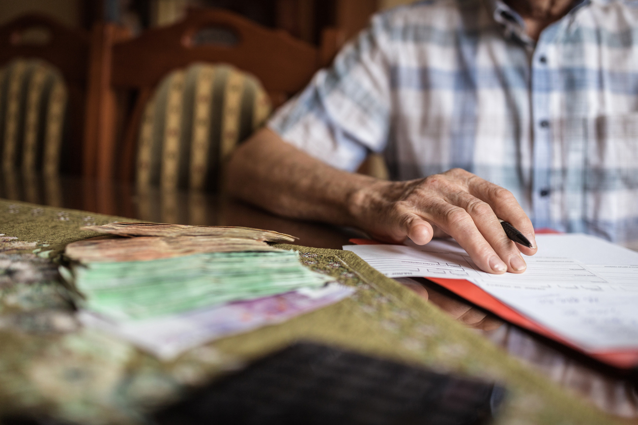 Man with no little finger signing papers at home