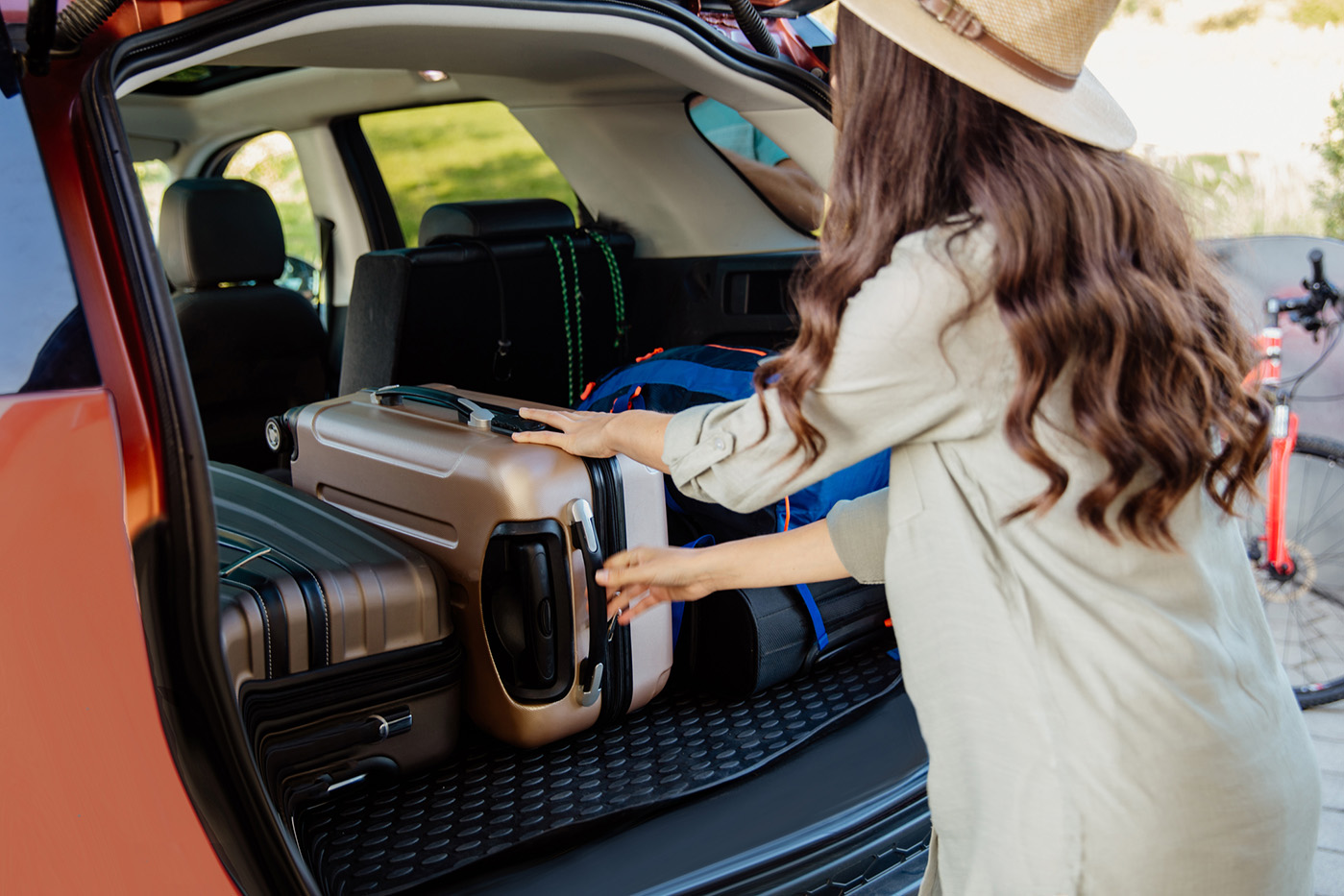 Rear view of a woman holding bag standing near car boot