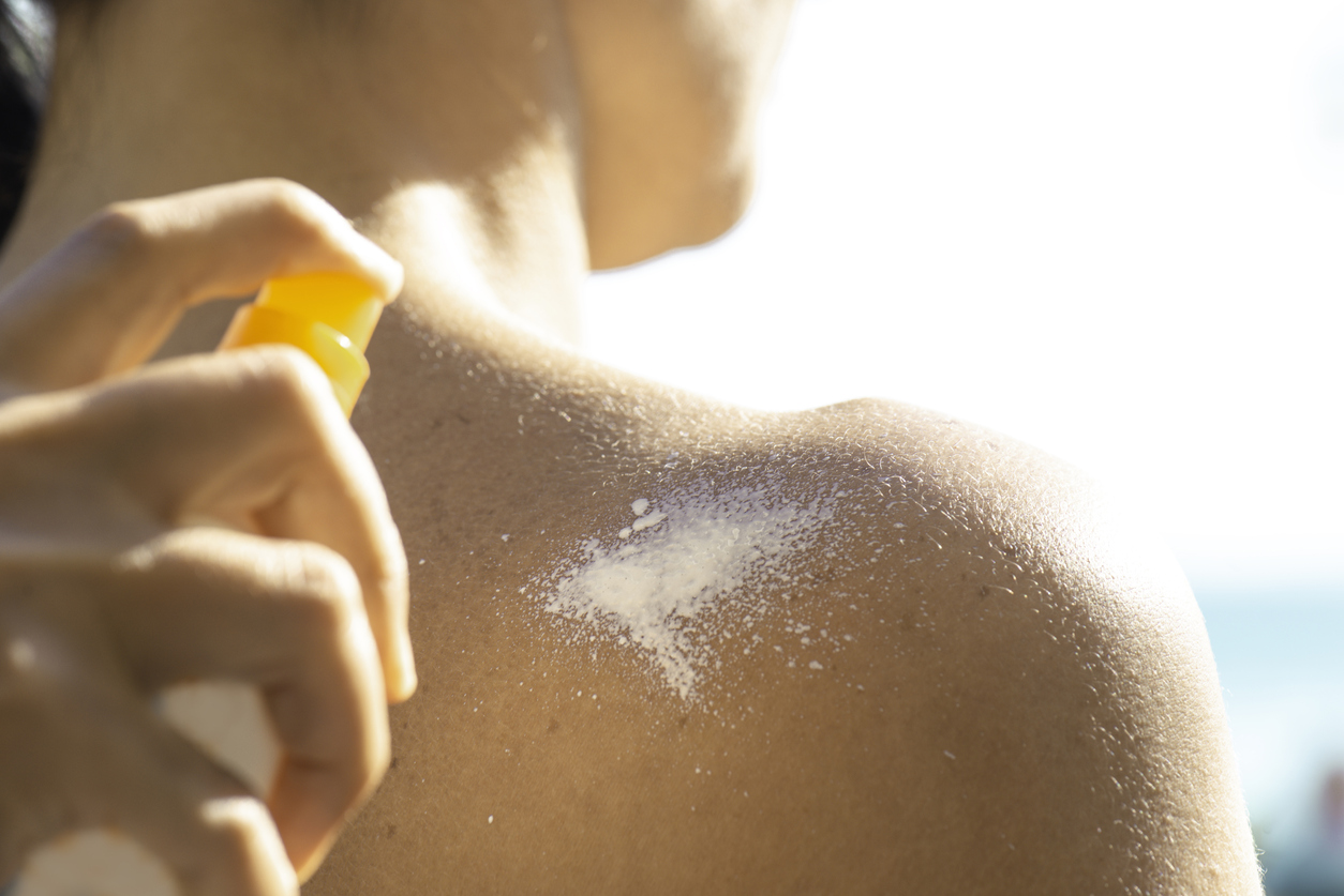 Woman hand applying suntan lotion to her friend’s shoulder.