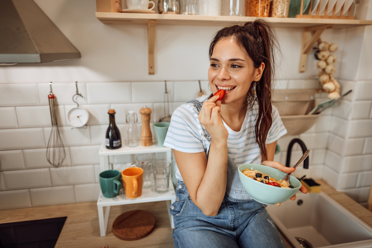 Woman enjoys breakfast on the kitchen in the morning