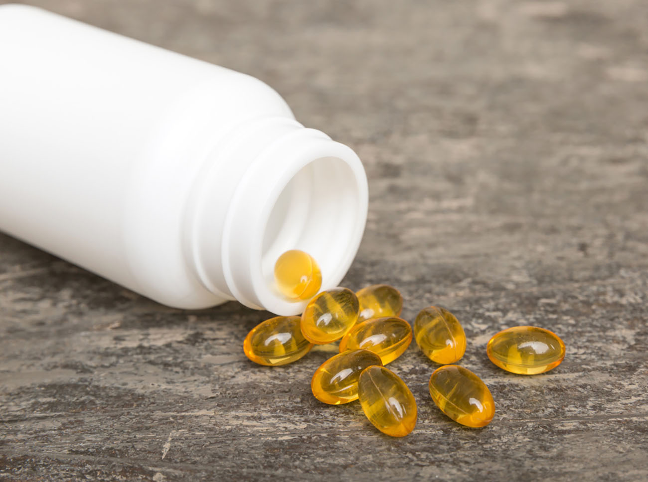 Omega-3 capsules lie in white bottle on a table background. Fish oil tablets top view. Biologically active additives. omega 6, omega 9, vitamin A, E, vitamin D, vitamin D3, evening primrose oil.