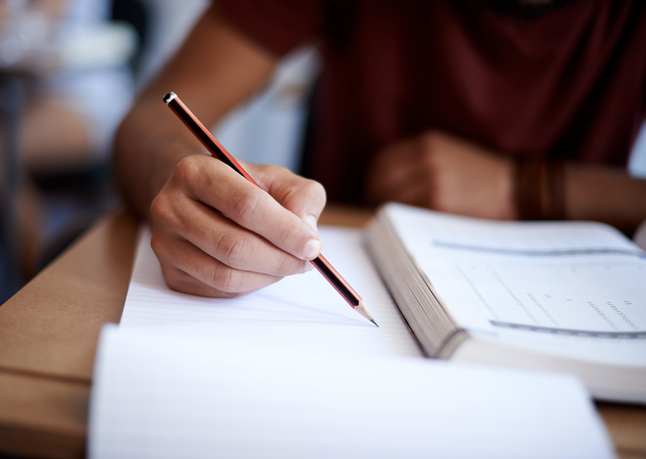 Closeup shot of a young man writing on a note pad