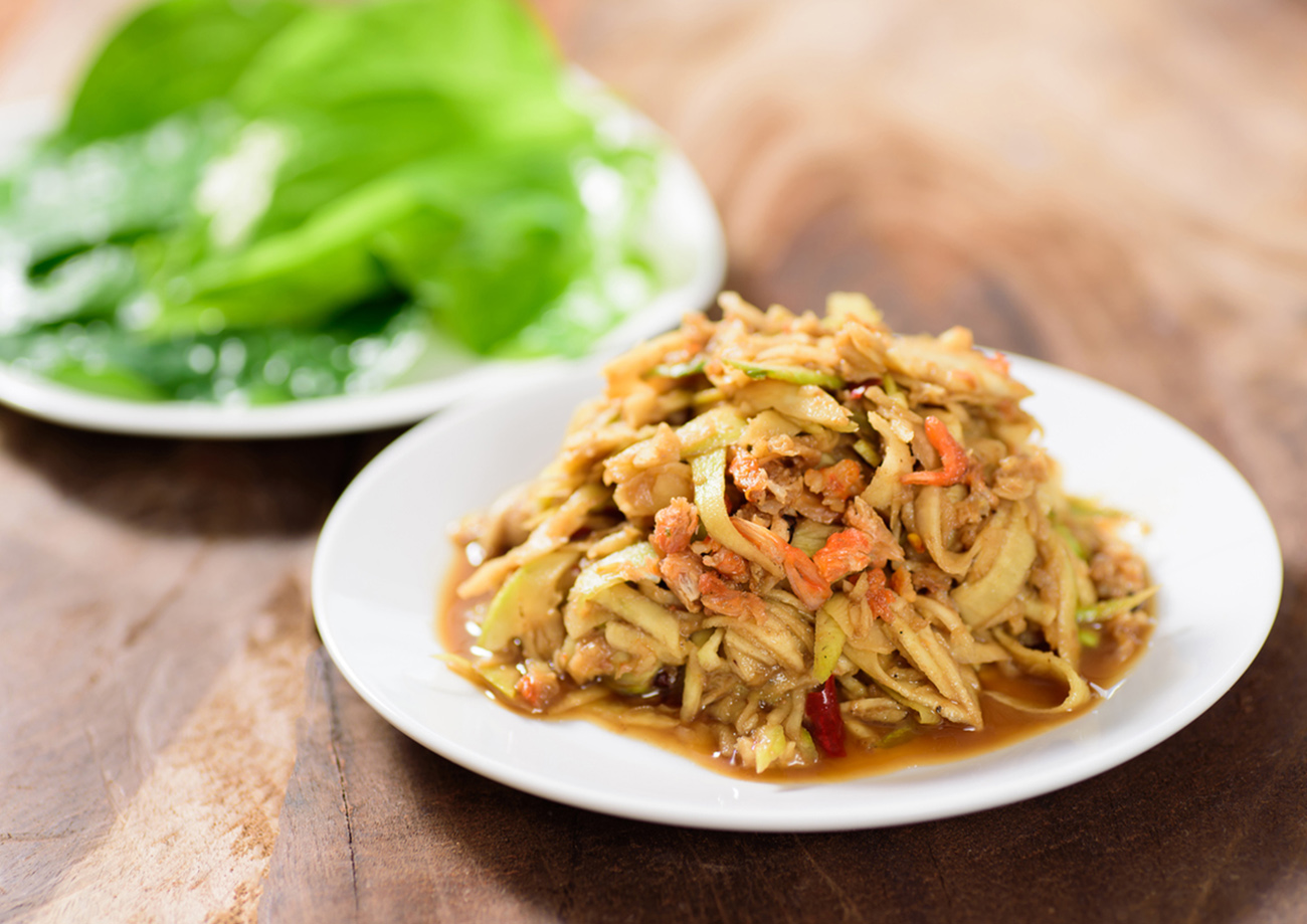 Thai food,spicy mango salad on white dish with vegetable