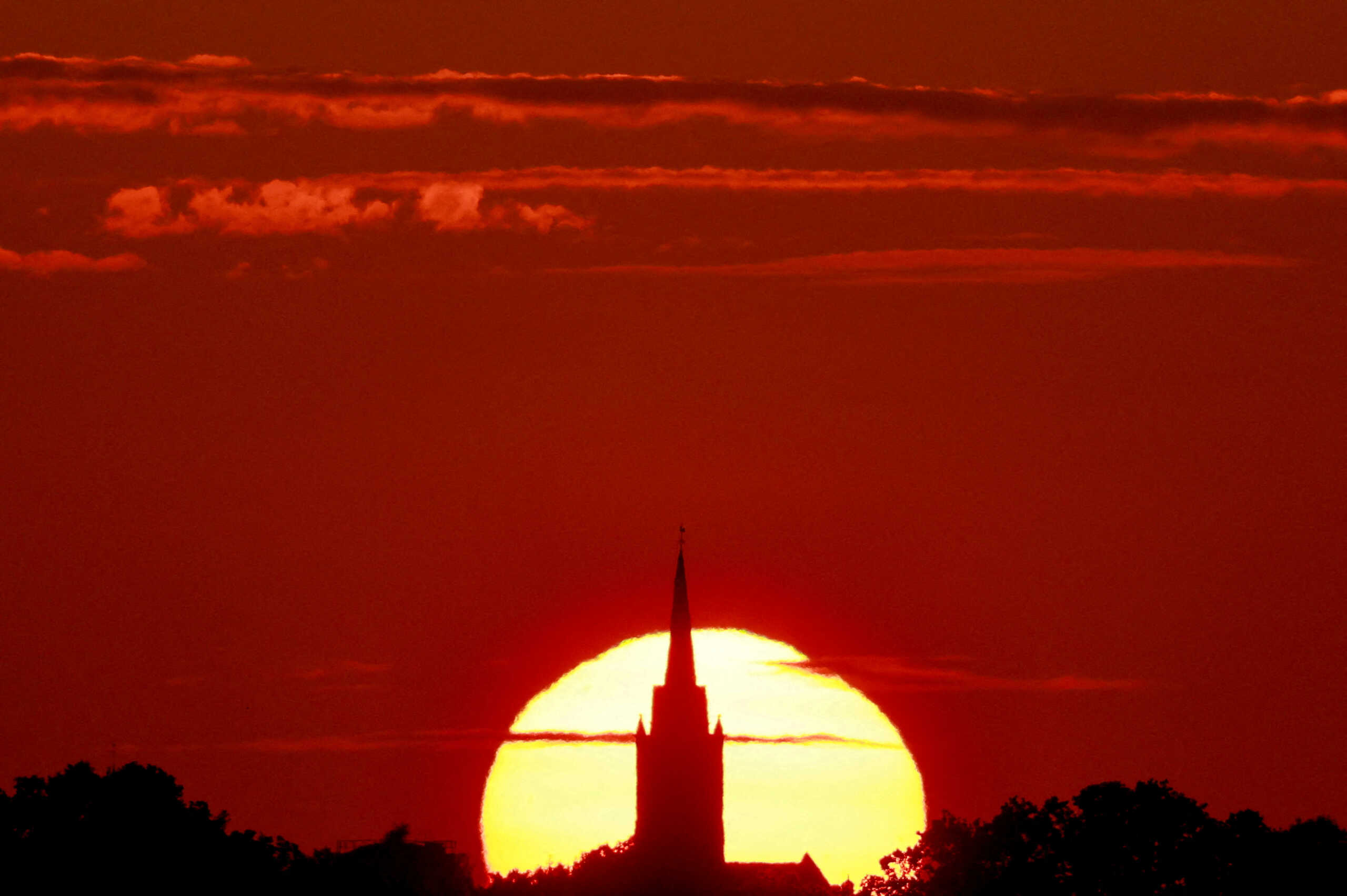 A church is pictured during sunset as a heat wave hits Europe, in Sancourt, France, July 12, 2023. REUTERS