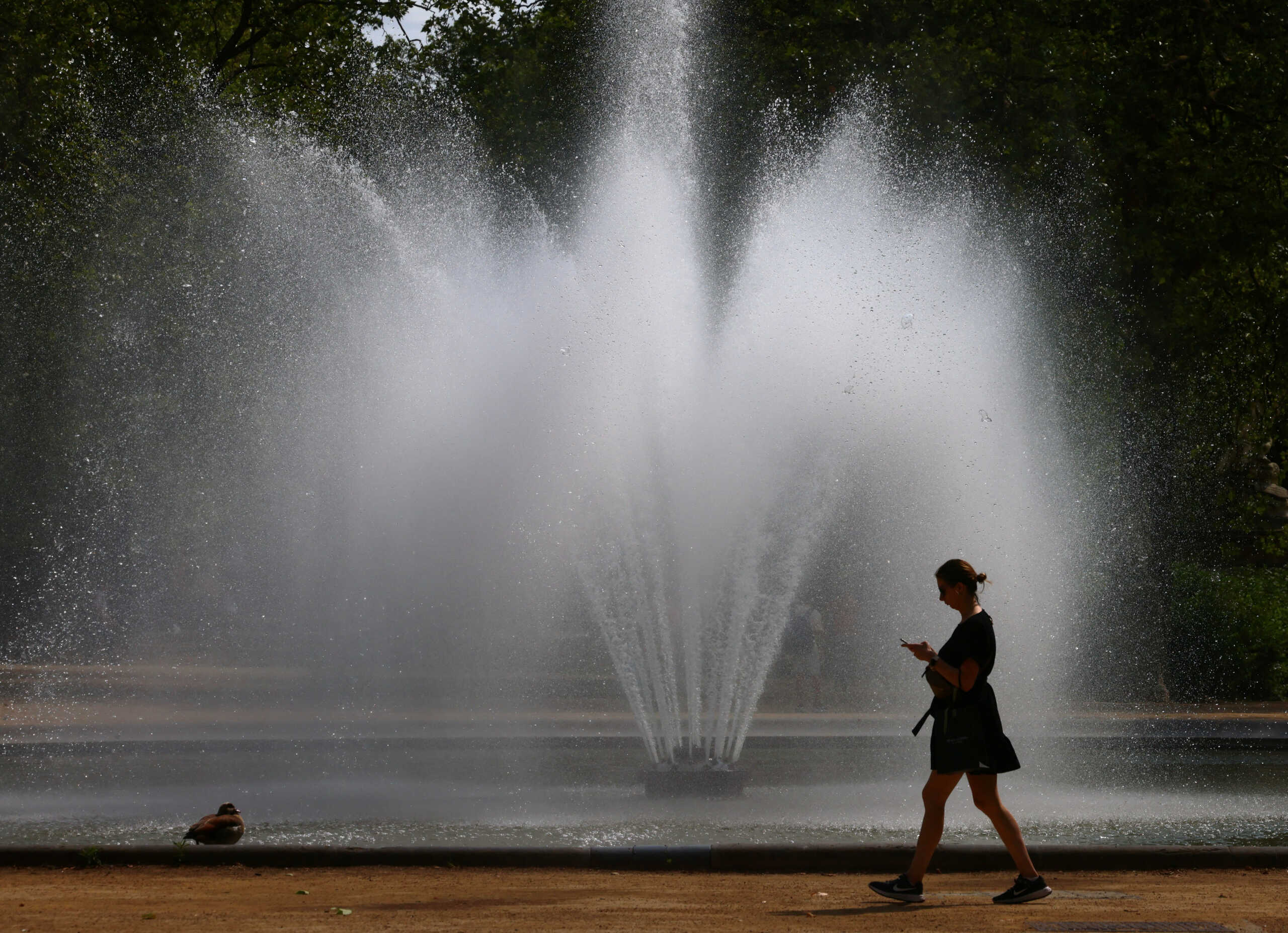 A woman walks past a fountain in a park as the heat wave grips Europe, in Brussels, Belgium June 26, 2023. REUTERS