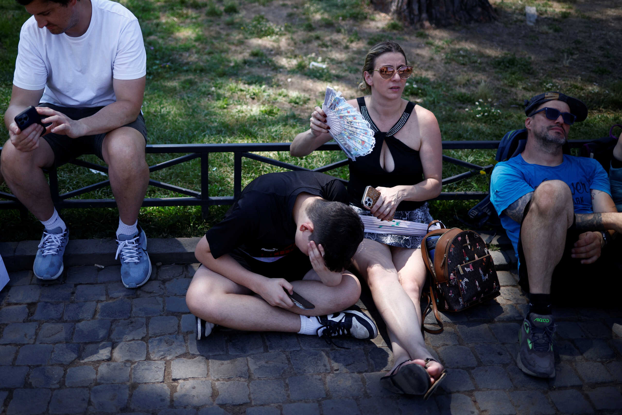 People sit in the shade near the Colosseum to shelter from the sun during a heatwave across Italy, in Rome, Italy July 11, 2023. REUTERS