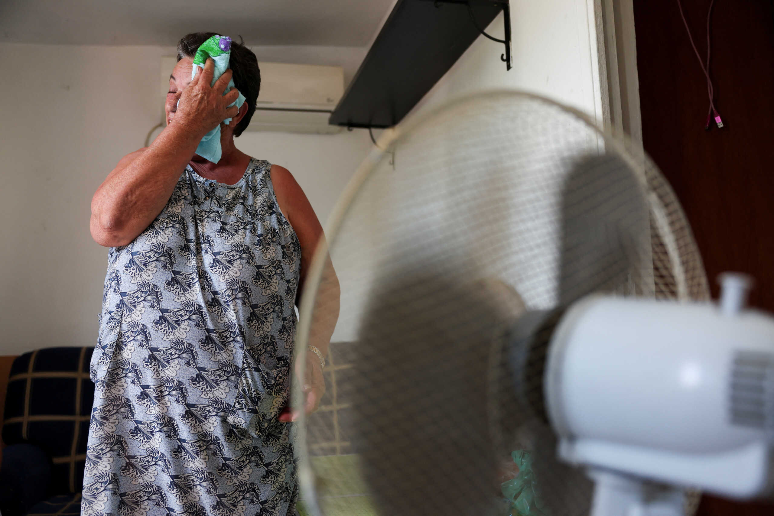 Monica Garcia, 65, wipes her sweat with a cloth while standing in front of a fan, as residents of Canada Real neighbourhood struggle with scorching temperatures amid first heatwave of the summer, in Madrid, Spain, June 26, 2023. The mother-of-three, who has lived at the shanty town for over 20 years, is waiting to be rehoused after a fire burnt her previous home. REUTERS