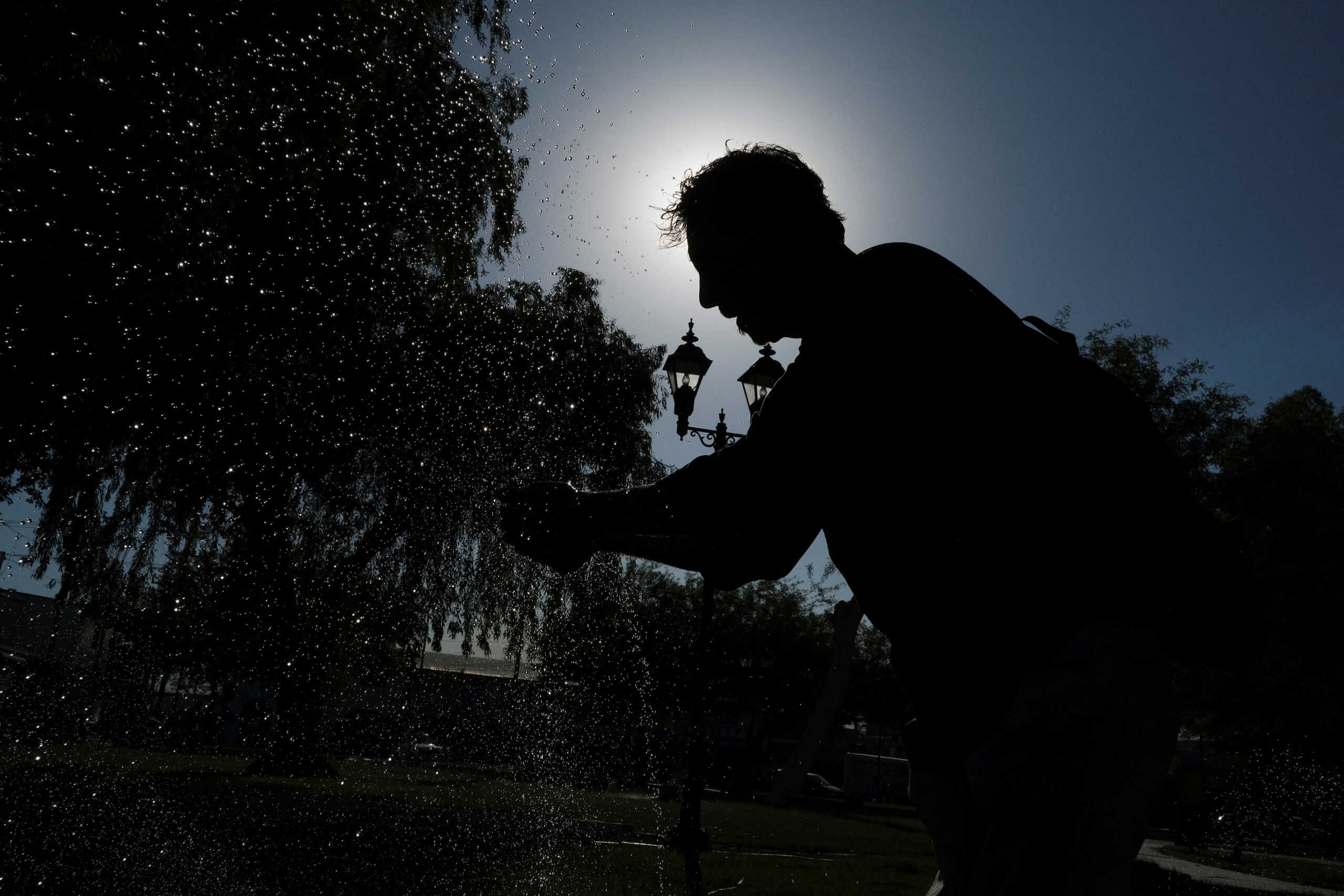 A man cools himself in a fountain under the intense heat as the temperature reaches 122 degrees Fahrenheit (50 Celsius), in Mexicali, Baja California state, Mexico July 5, 2023. REUTERS
