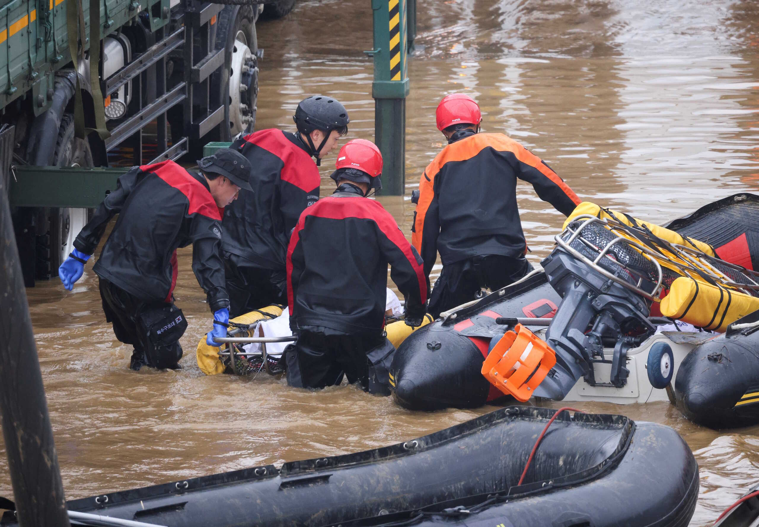 Rescue workers carry the body of a victim recovered during a search and rescue operation near an underpass that has been submerged by a flooded river caused by torrential rain in Cheongju, South Korea, July 16, 2023.   REUTERS