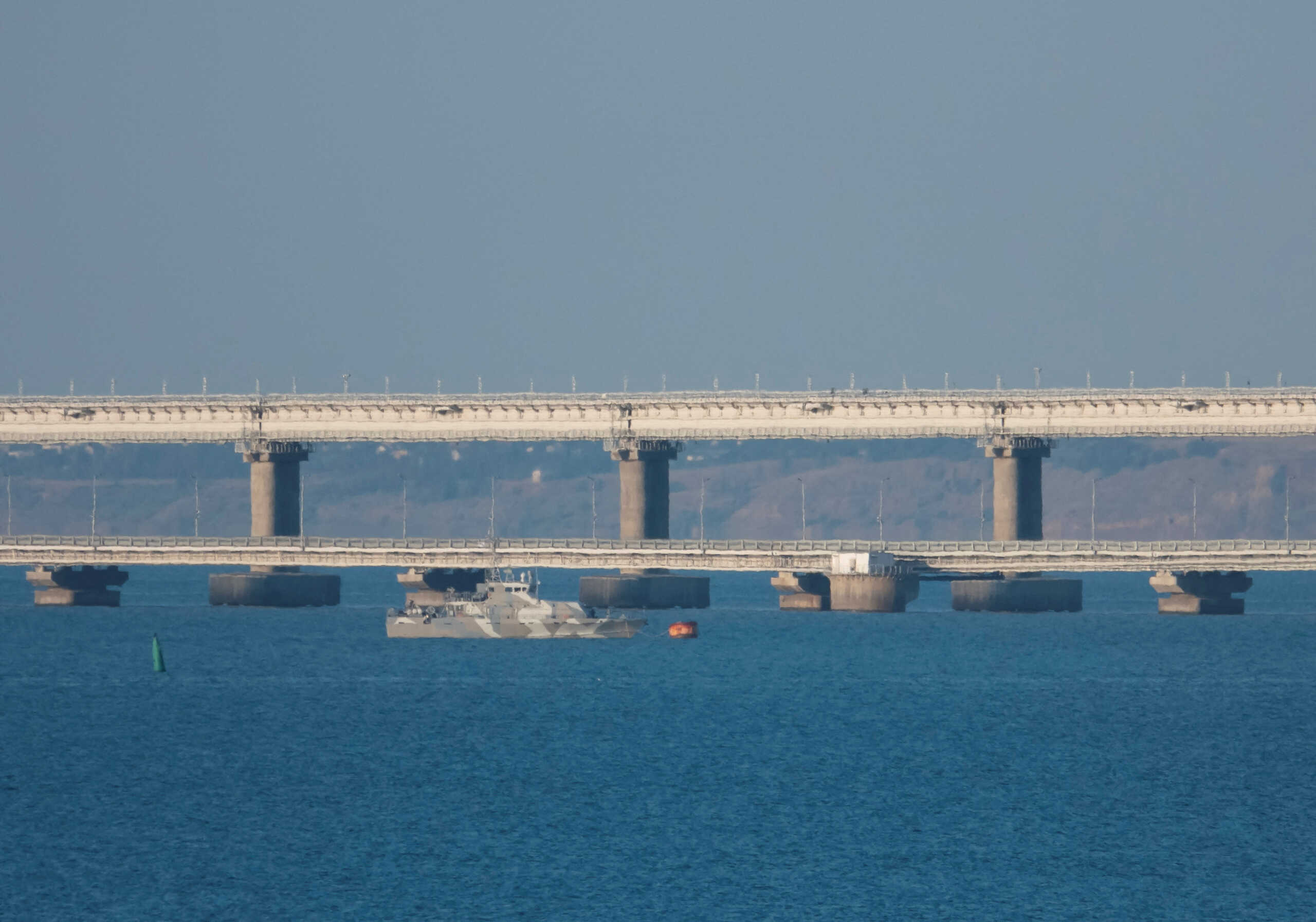 An armed ship sails next to Crimean bridge connecting the Russian mainland with the peninsula across the Kerch Strait, Crimea, July 17, 2023.  REUTERS