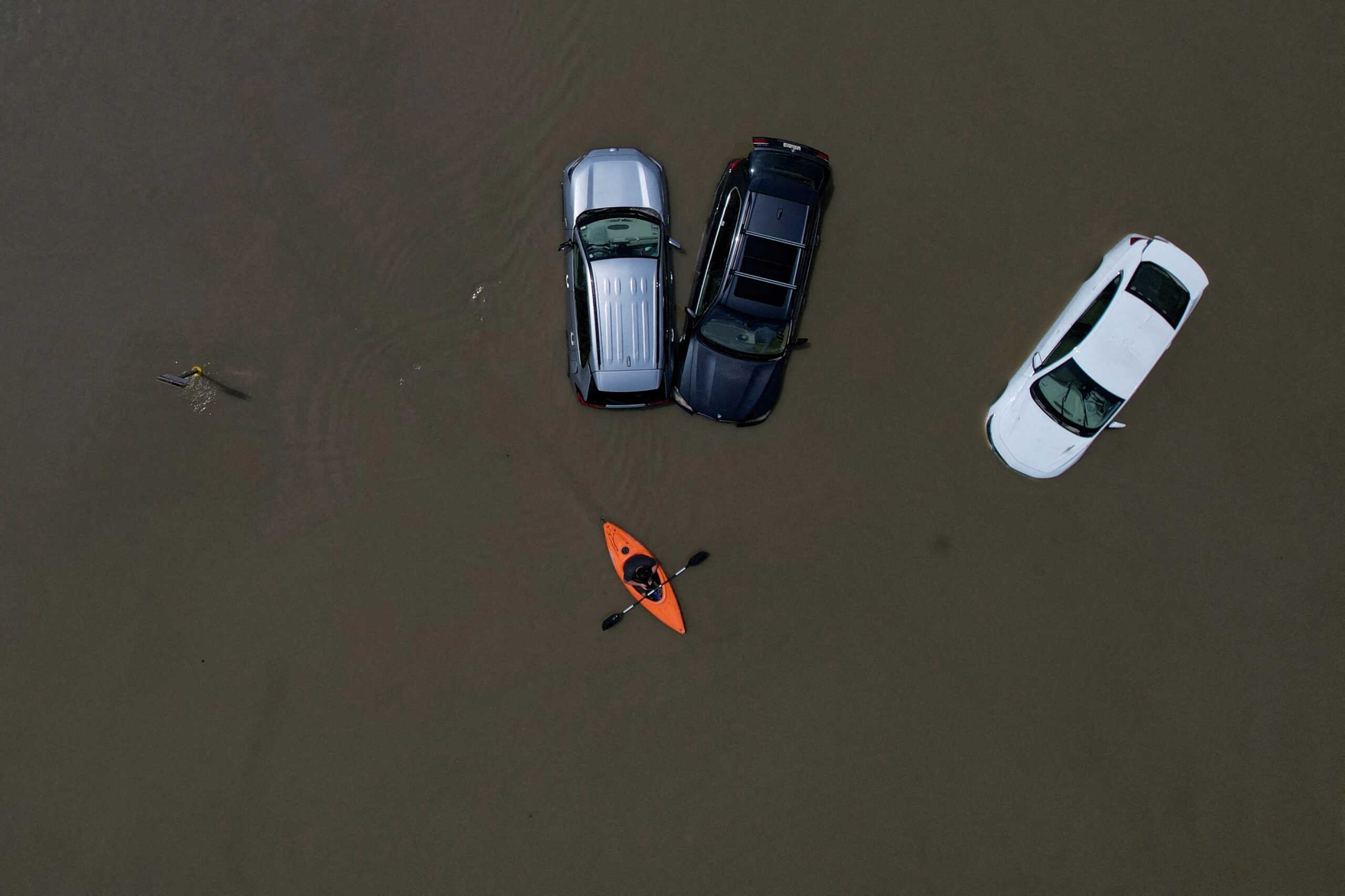 FILE PHOTO: A person in a canoe passes cars partially submerged by flood waters from recent rain storms in Montpelier, Vermont, U.S., July 11, 2023.     REUTERS