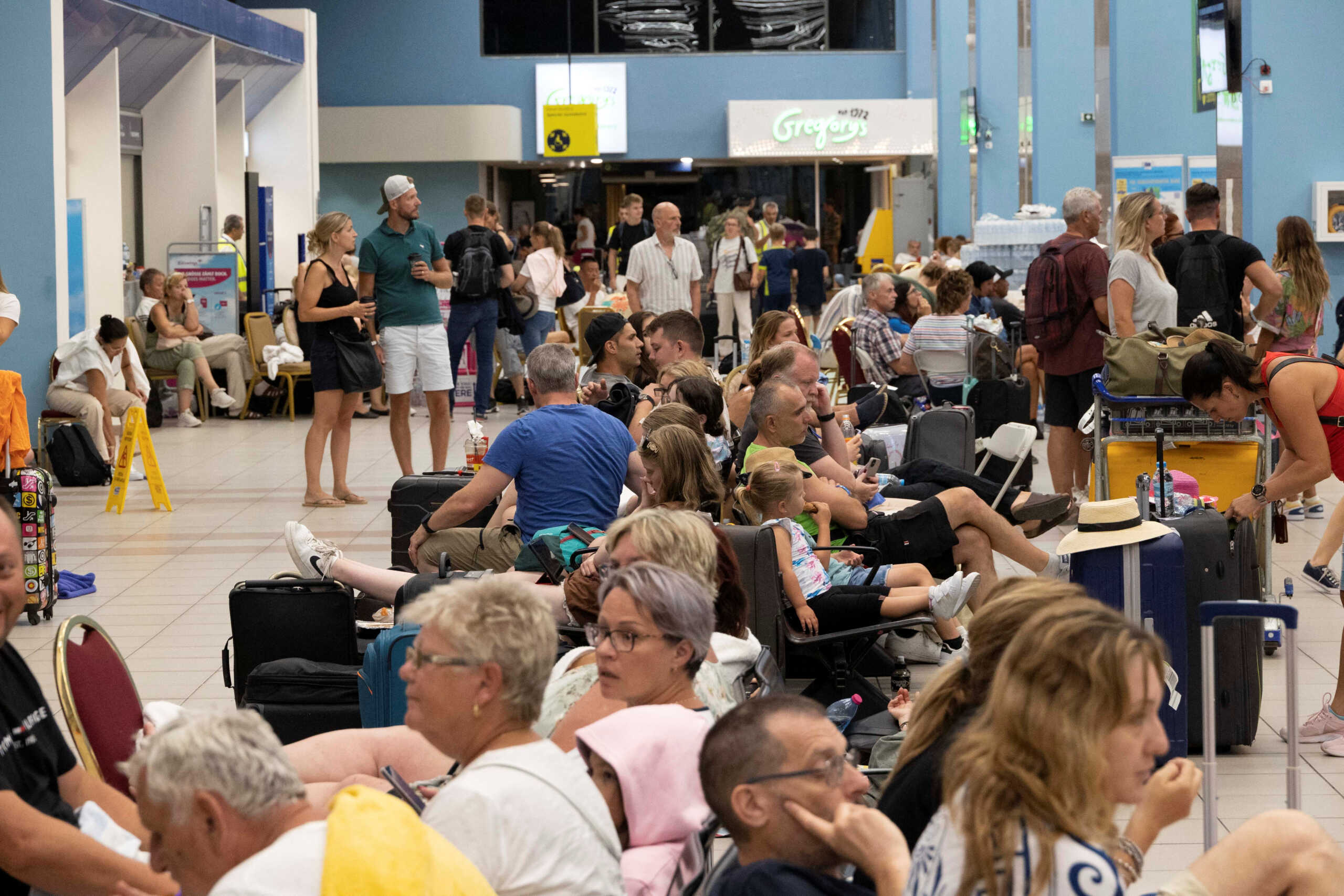 Tourists wait for departing planes at the airport, after being evacuated following a wildfire on the island of Rhodes, Greece, July 24, 2023. REUTERS
