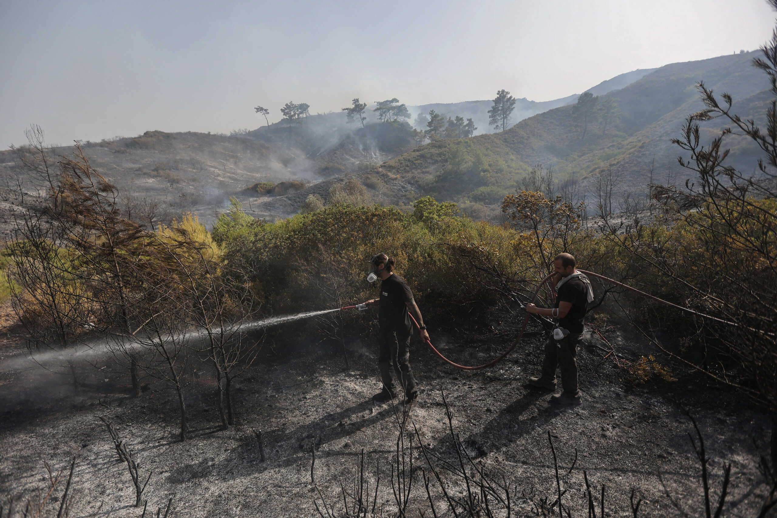 Volunteers try to extinguish a wildfire burning near the village of Asklipieio, on the island of Rhodes, Greece, July 27, 2023. REUTERS
