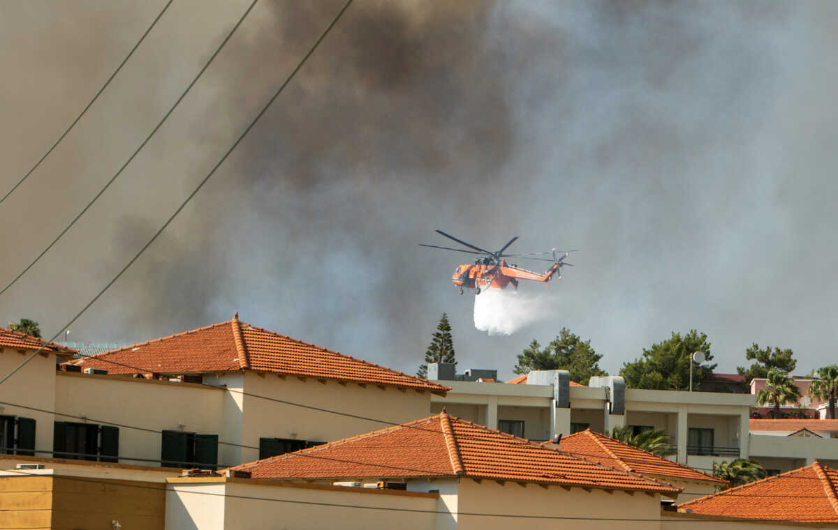 A firefighting helicopter drops water over a wildfire burning near Lindos, on the island of Rhodes, Greece, July 22, 2023. REUTERS
