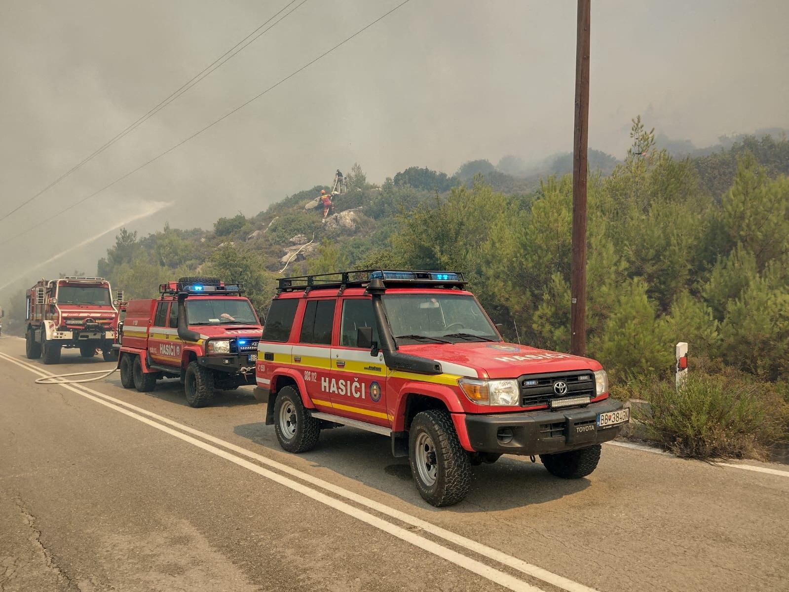 Firetrucks line up as firefighters try to extinguish a wildfire burning near Laerma, Rhodes Island, Greece, July 22, 2023. HAZZ Slovak Fire and Rescue Services