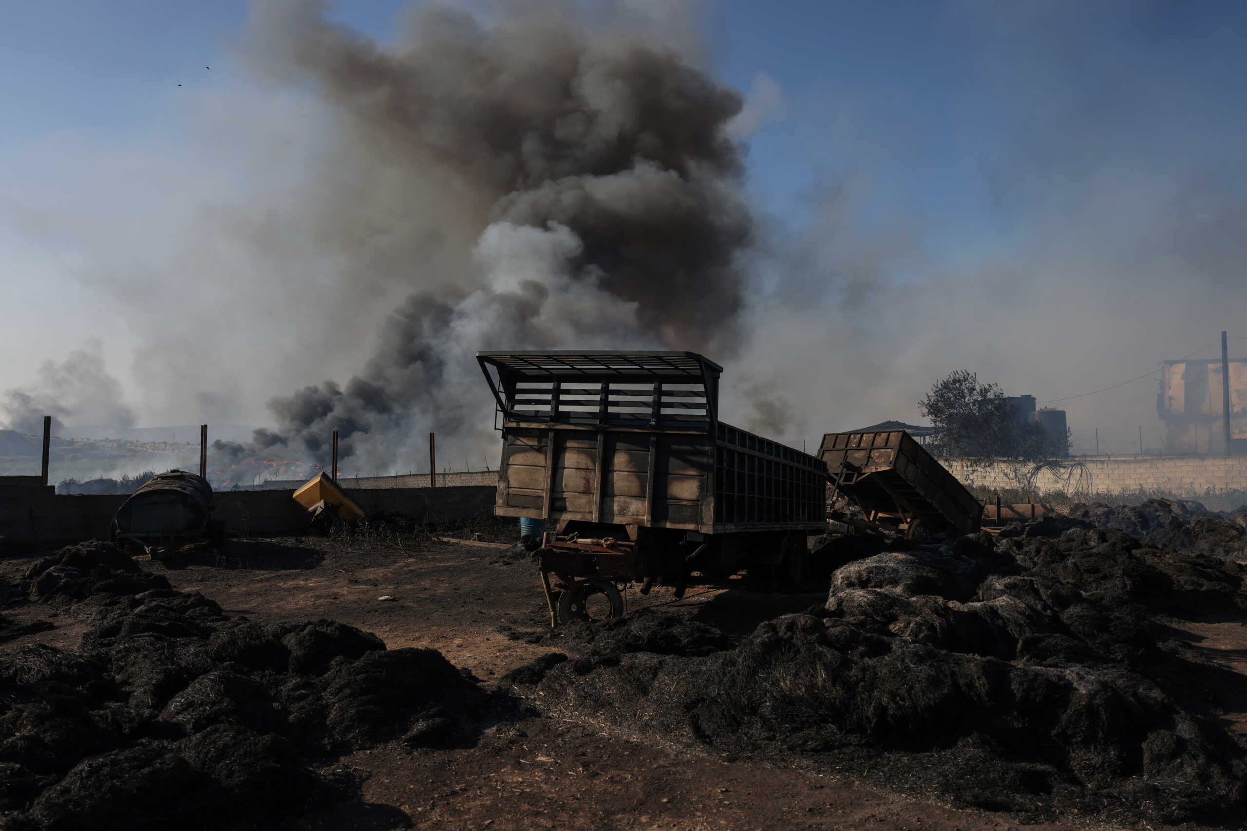 Destroyed truck carriages are seen in a factory yard as a wildfire burns at the city of Volos, in central Greece, July 27, 2023. REUTERS