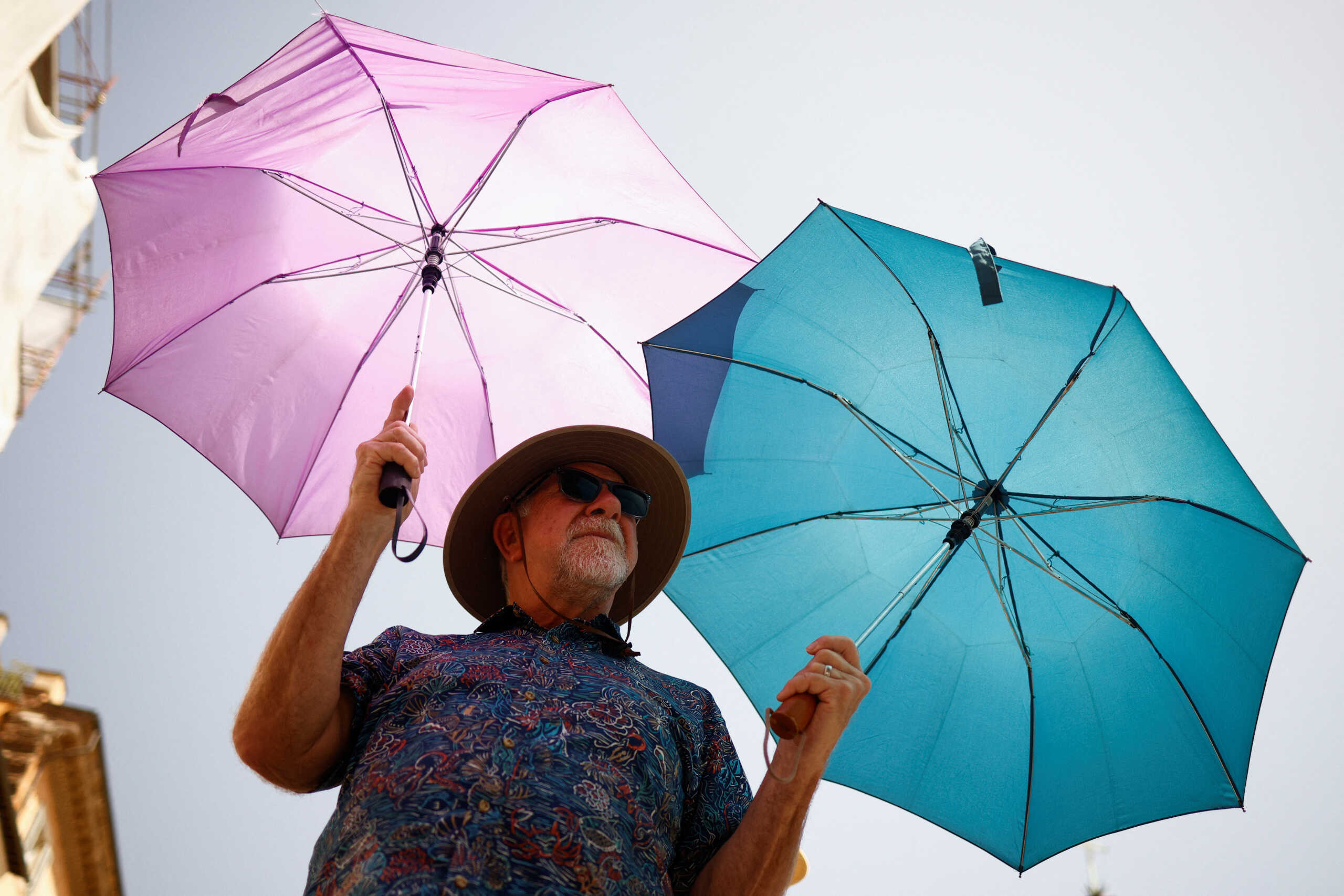Mike Eggehorn from California uses two umbrellas to shelter from the sun as he queues to enter the Pantheon, during a heatwave across Italy, as temperatures are expected to cool off in the Italian capital, in Rome, Italy July 19, 2023. REUTERS