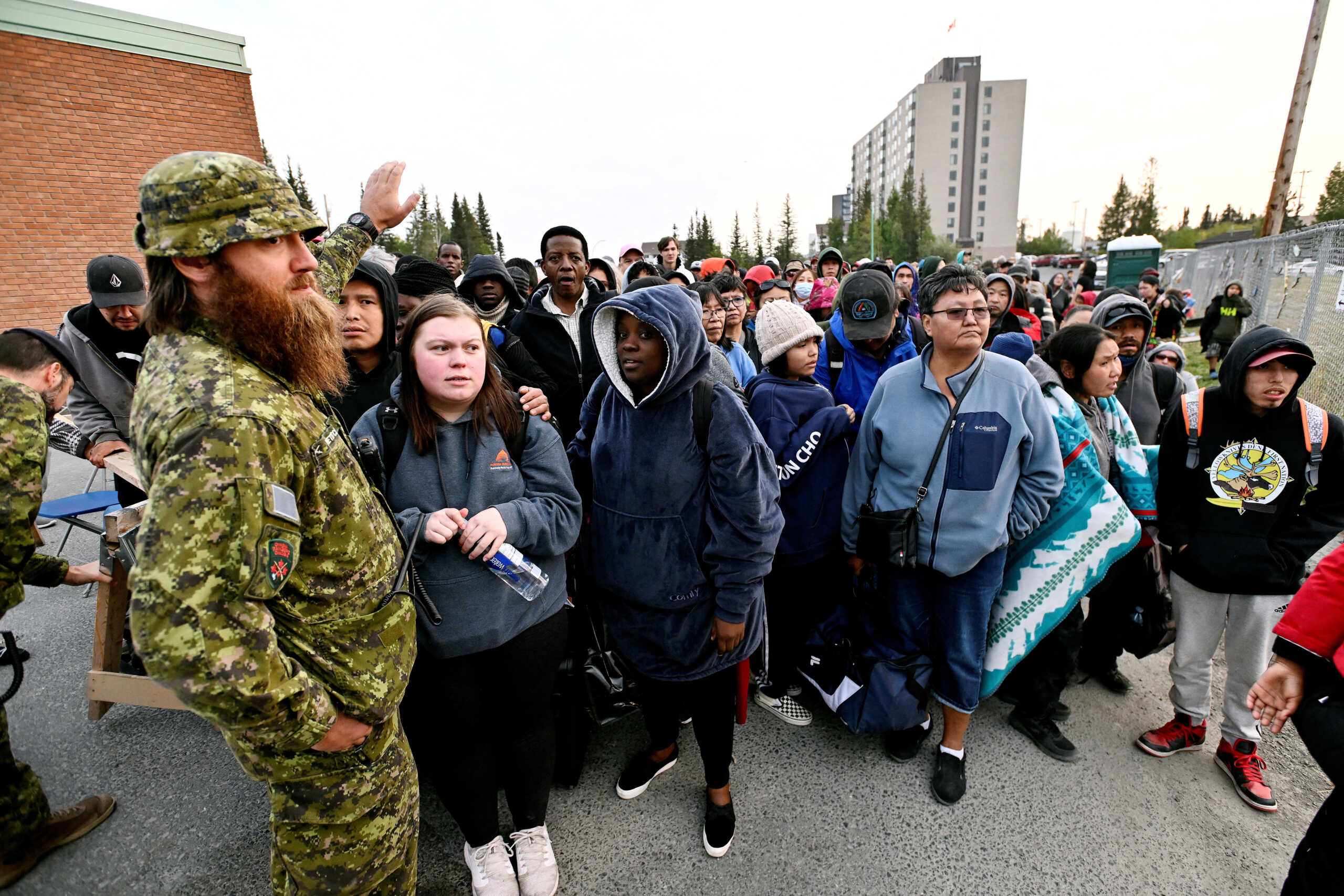 People line up outside of a local school to register to be evacuated, as wildfires threatened the Northwest Territories town of Yellowknife, Canada, August 17, 2023.  REUTERS
