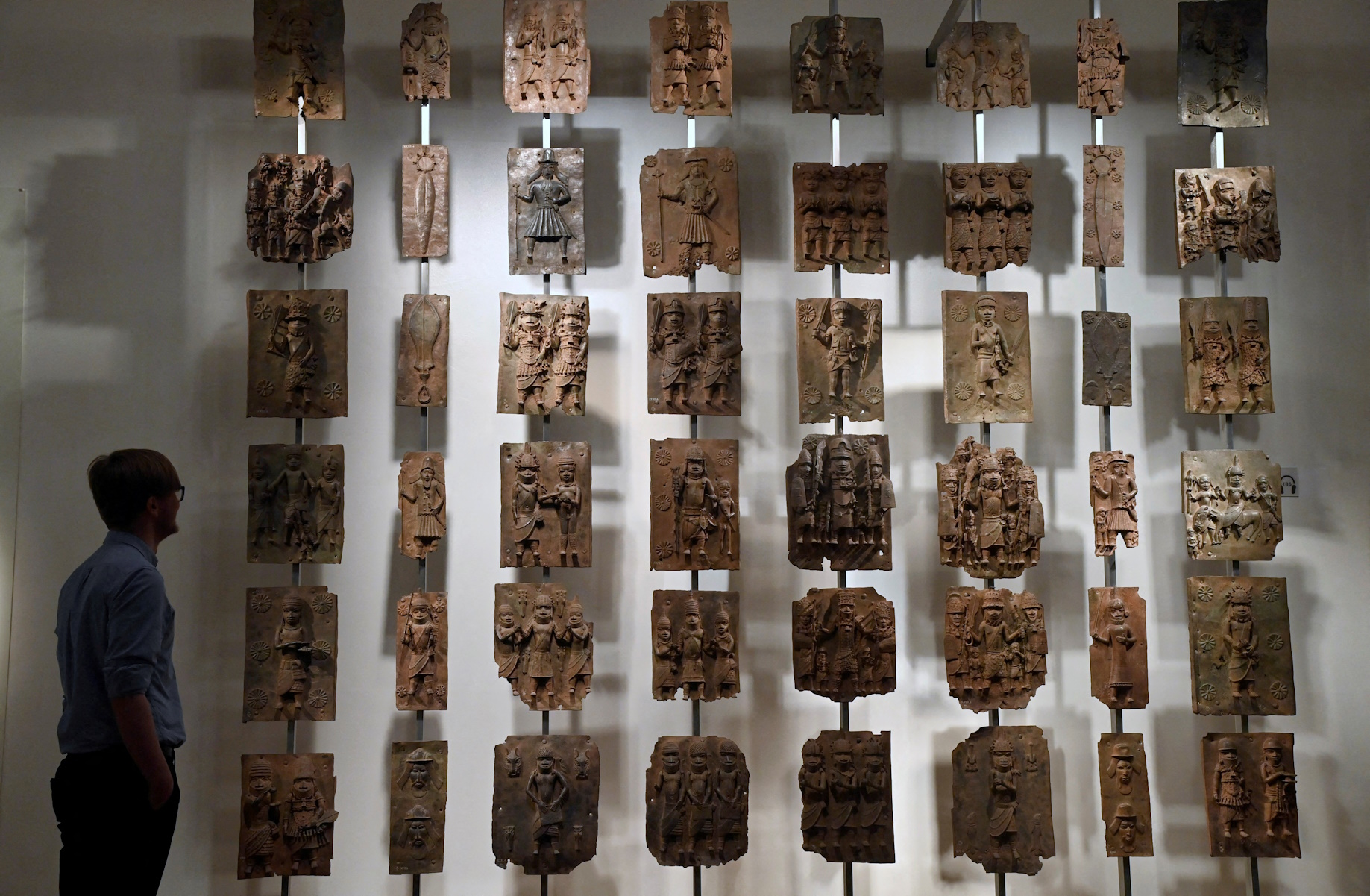 FILE PHOTO: An employee poses as he views examples of Benin bronzes which, together with collections such as the Parthenon sculptures, are the subject of talks of their return to countries of origin, displayed at the British Museum in London, Britain, January 25, 2023. REUTERS