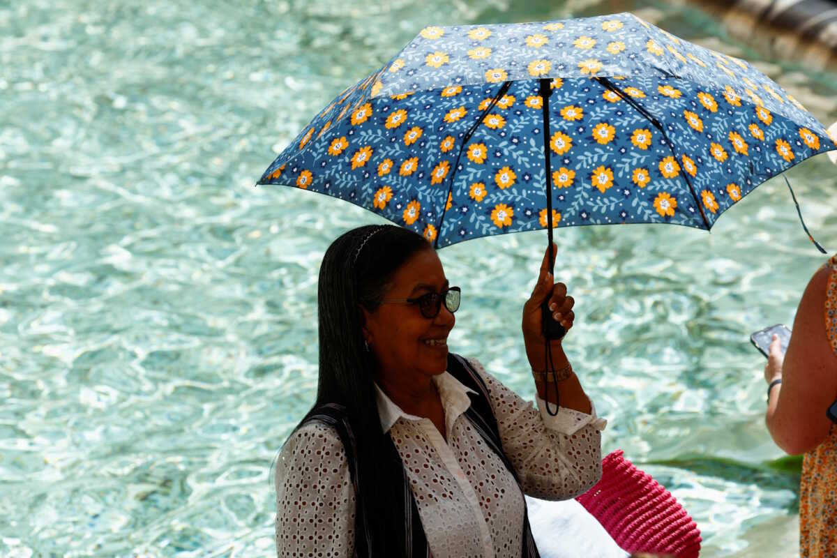 A person holds an umbrella as she takes shelter from the sun near Trevi Fountain during a heatwave across Italy as temperatures are expected to cool off in Rome, Italy, July 20, 2023. REUTERS