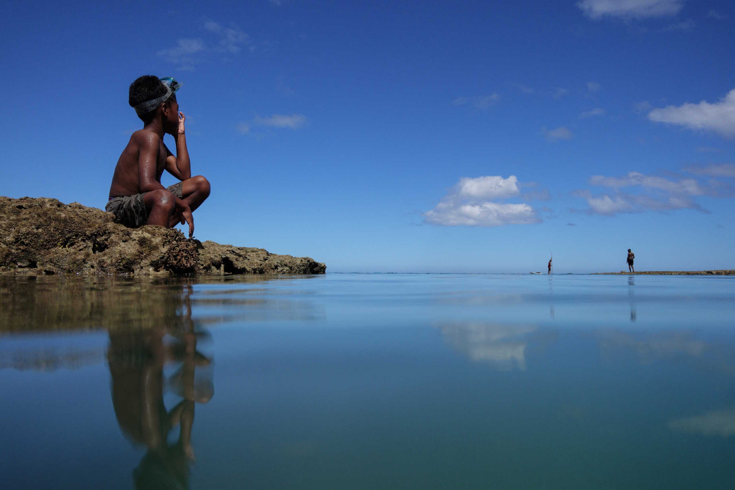 Local boy Ratukali Madanawa, 8, takes a break from diving in the sea at Serua Village, Fiji, July 14, 2022. As the community runs out of ways to adapt to the rising Pacific Ocean, the 80 villagers face the painful decision whether to move.        REUTERS