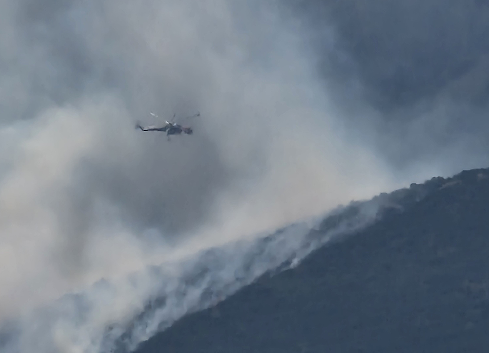 A helicopter overflies the area as a wildfire spreads in Avlonas, Attica, Greece, August 24, 2023 in this picture obtained from social media. Instagram @olakala