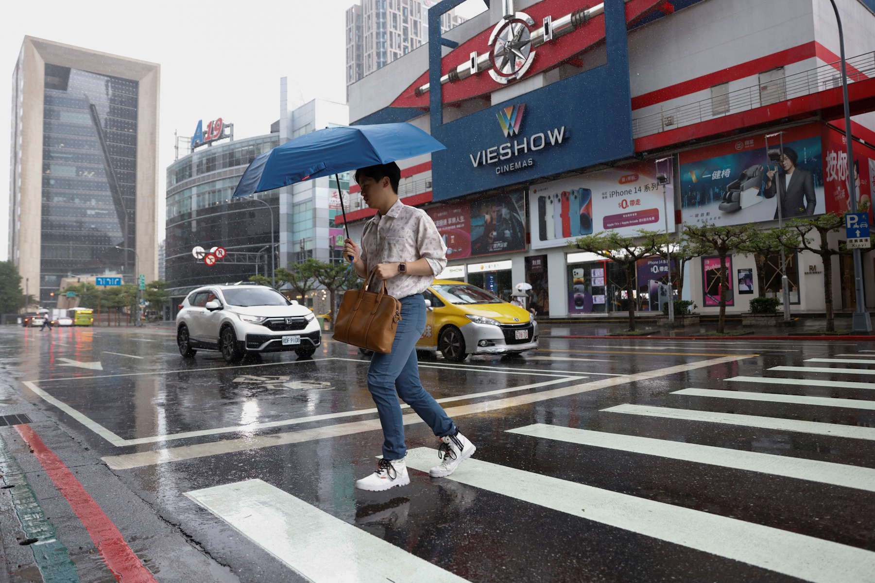 A man crosses the street as it rains at a commercial area where most stores are closed amid warnings of floods and high winds in northern Taiwan due to Typhoon Khanun, in Taipei, Taiwan, August 3, 2023. REUTERS