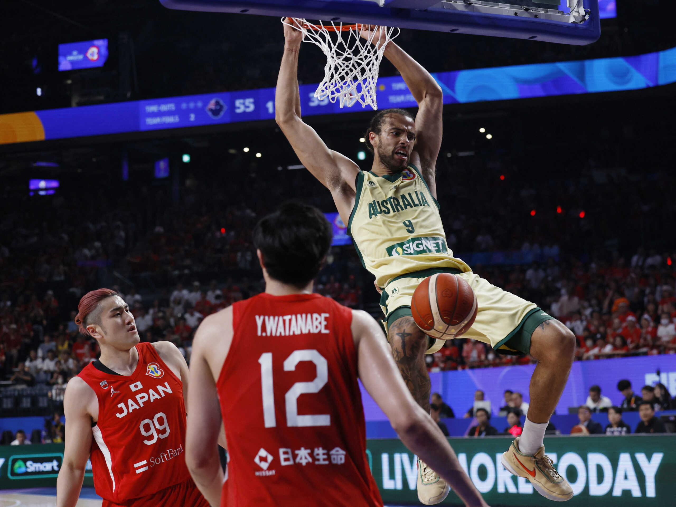 Basketball - FIBA World Cup 2023 - First Round - Group E - Australia v Japan - Okinawa Arena, Okinawa, Japan - August 29, 2023 Australia's Xavier Cooks scores a basket as Japan's Koya Kawamata and Japan's Yuta Watanabe look on REUTERS