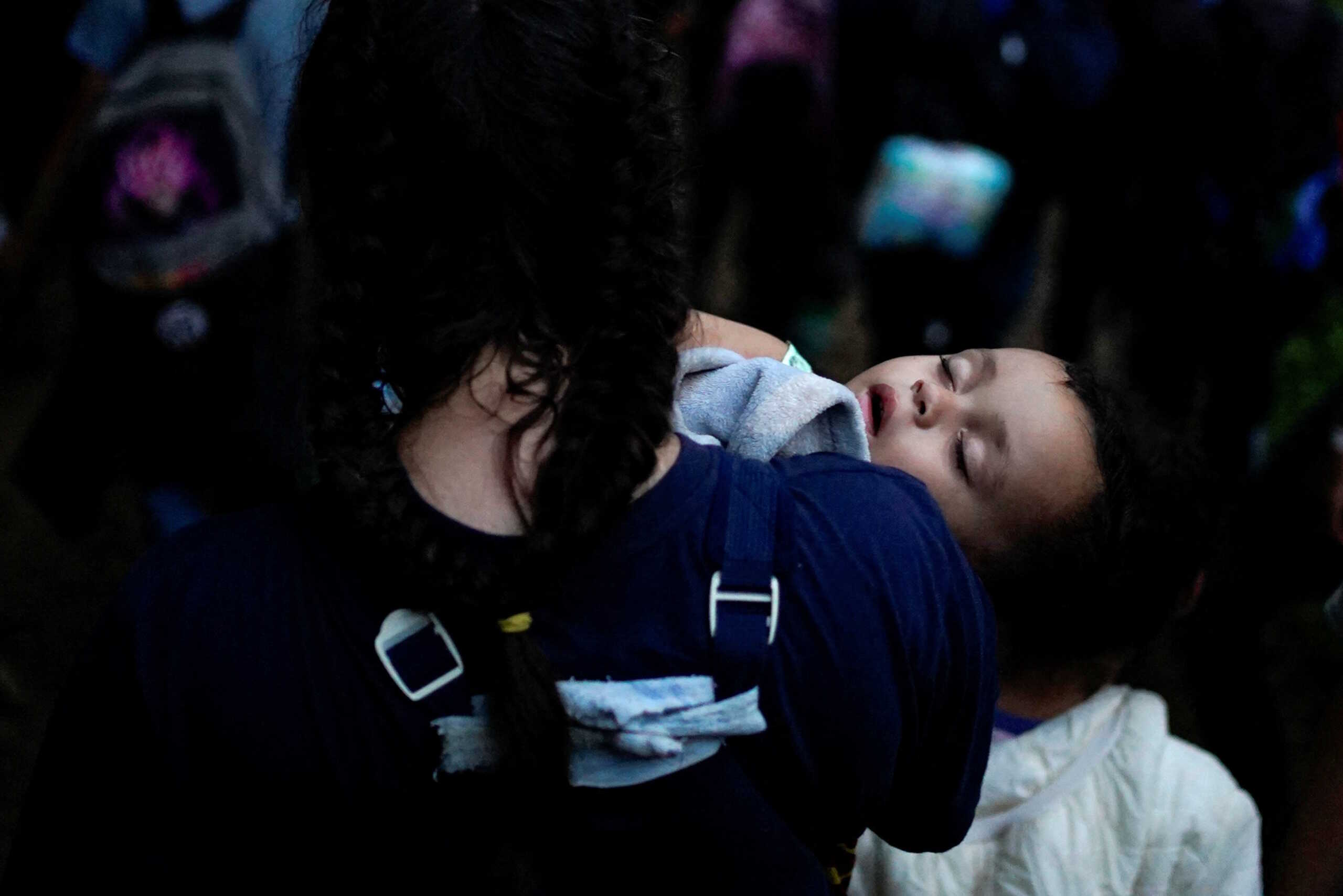 A Venezuelan migrant holds her sleeping baby before walking a path through the Darien Gap, as they continue their journey to the U.S. border, in Acandi, Colombia July 9, 2023. REUTERS