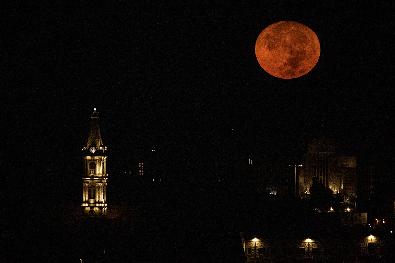 A supermoon, also known as a Blue Moon is seen above the clocktower of the Monastery of Saint Saviour in Jerusalem's Old City, August 30, 2023. REUTERS