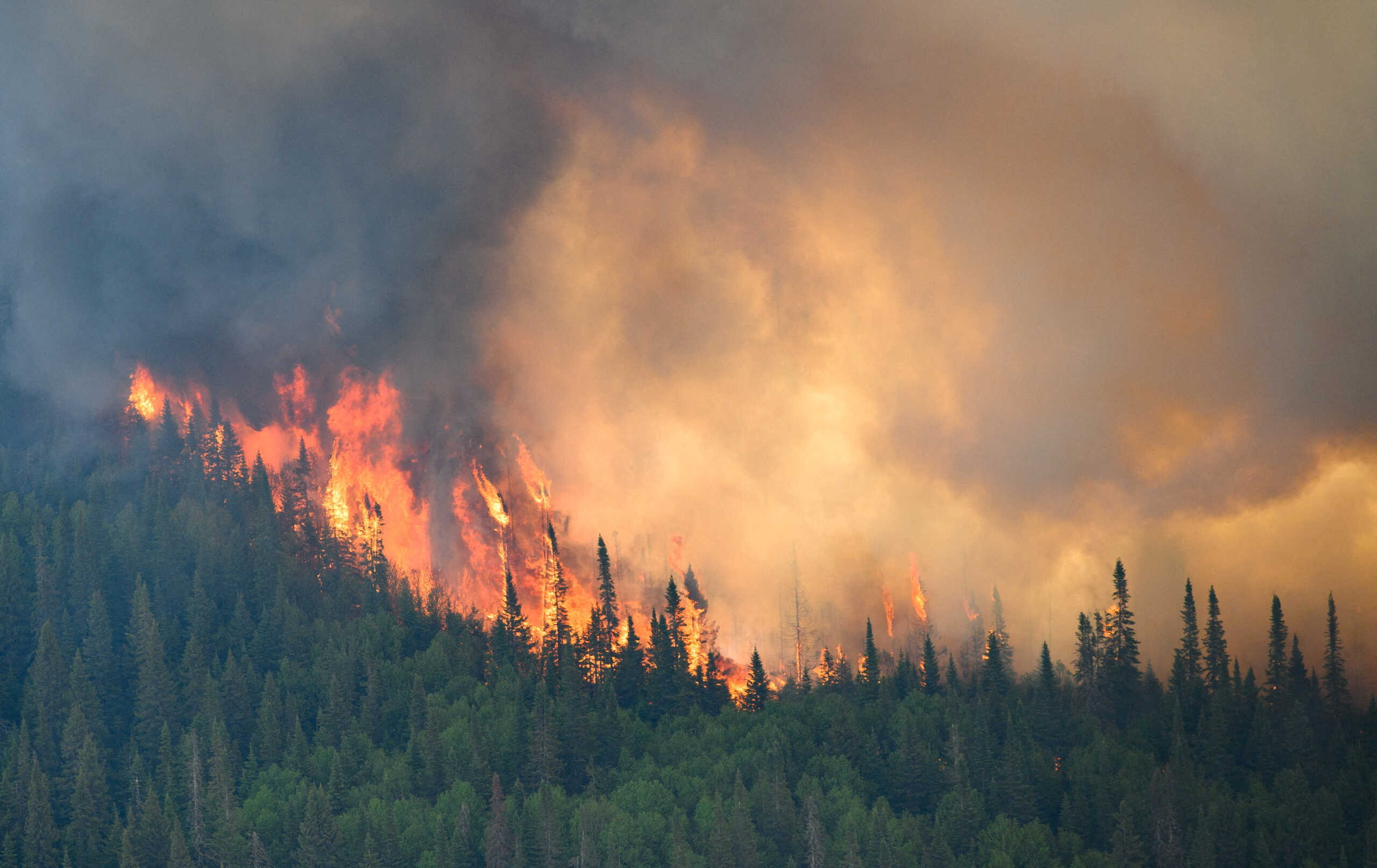 Flames reach upwards along the edge of a wildfire as seen from a Canadian Forces helicopter surveying the area near Mistissini, Quebec, Canada June 12, 2023.   Cpl Marc-Andre Leclerc