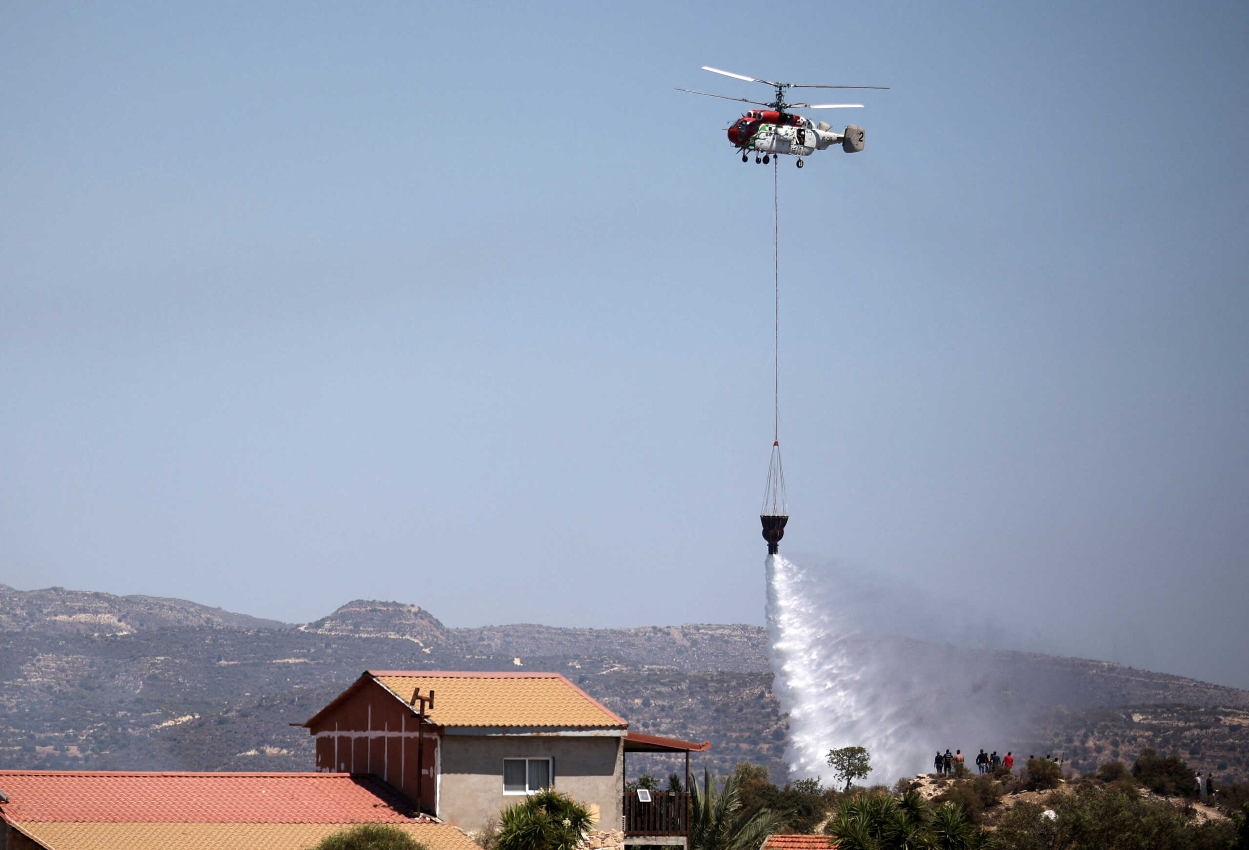 A firefighting helicopter makes a water drop during a wildfire near the village of Alassa, Cyprus August 5, 2023. REUTERS
