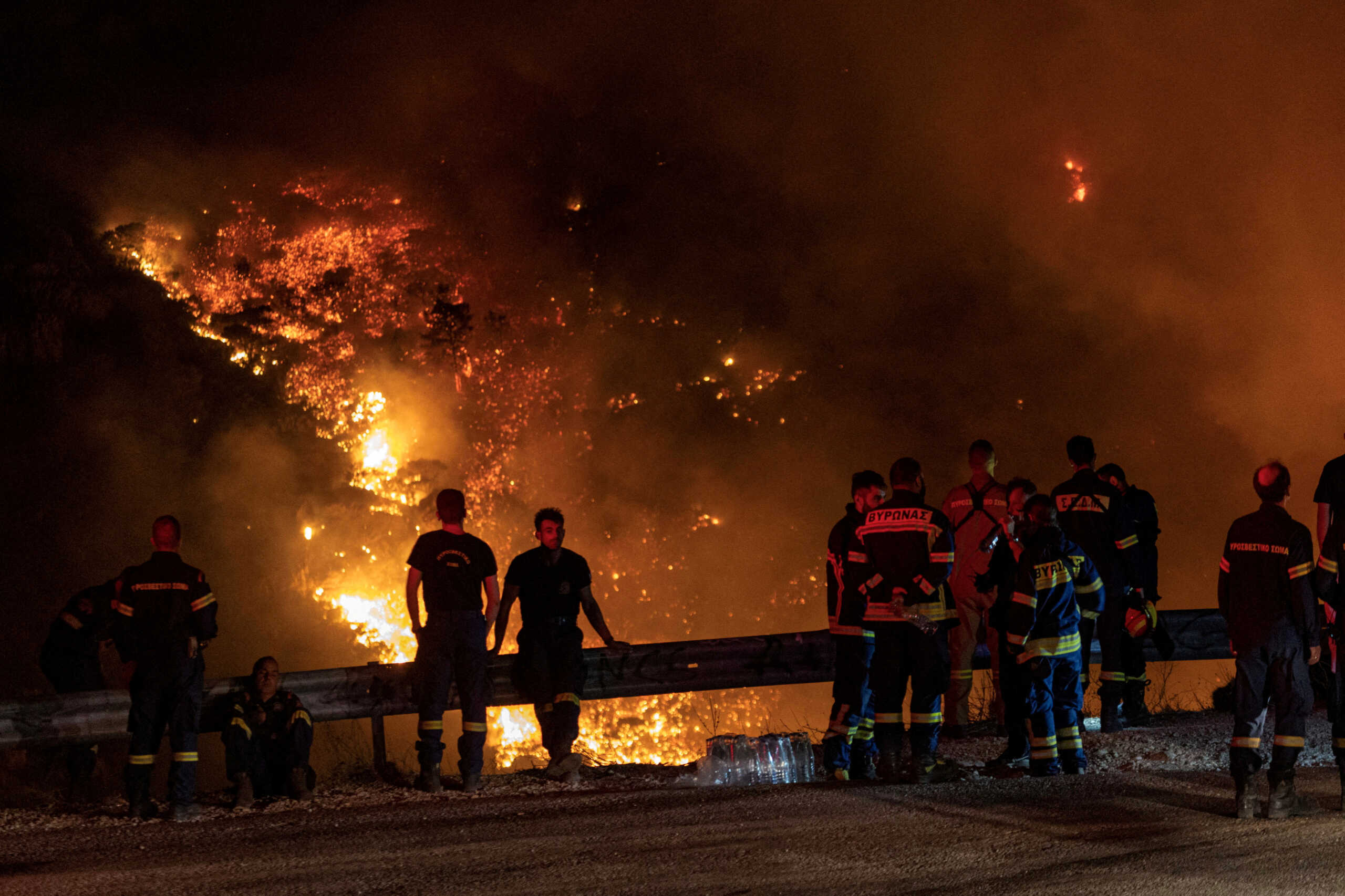 Firefighters look at a wildfire burning on Mount Parnitha, in Athens, Greece, August 24, 2023. REUTERS