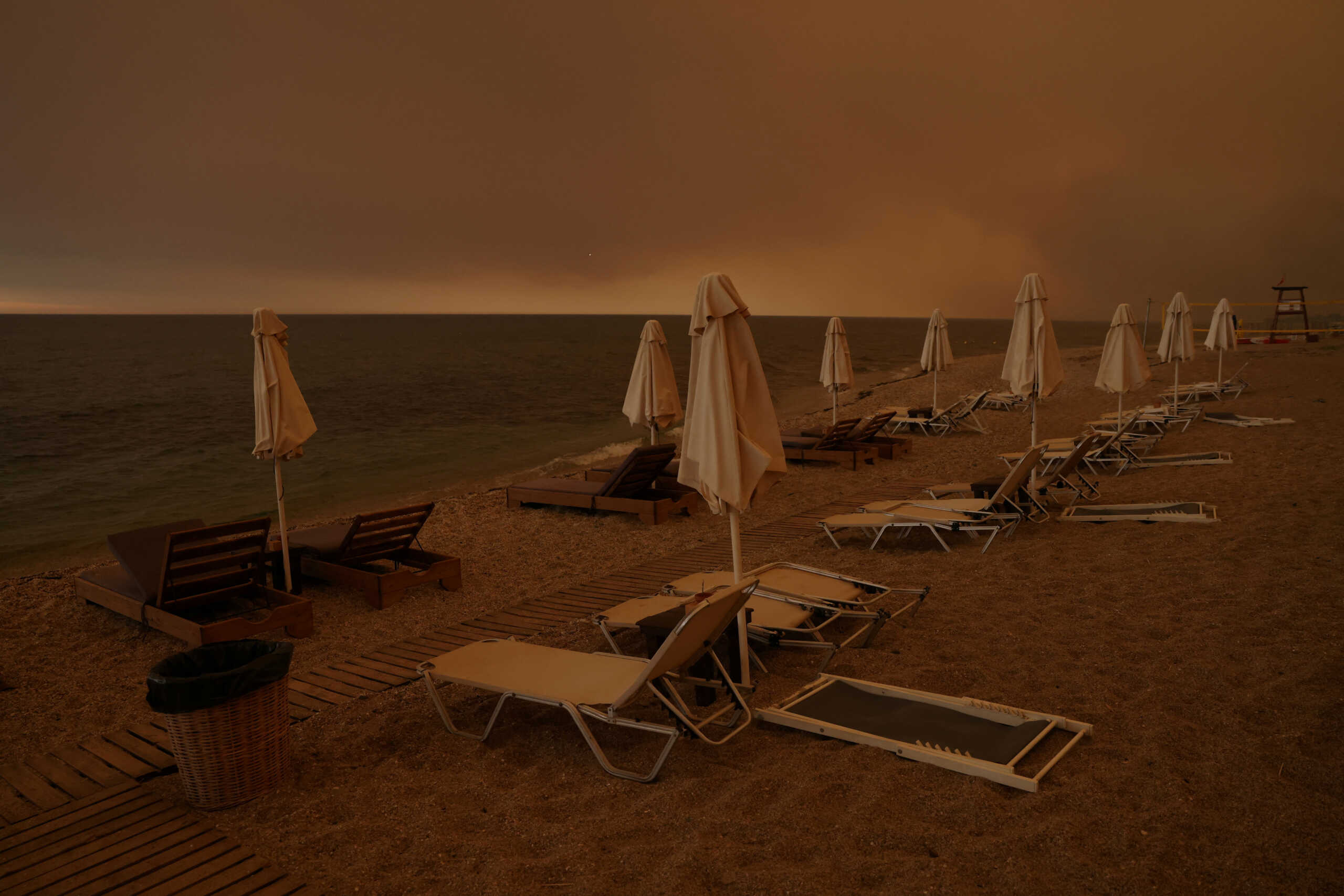 Smoke rises next to sunbeams and umbrellas as a wildfire burns, at the beach of the village of Dikella, near Alexandroupolis, in the region of Evros, Greece, August 22, 2023. REUTERS
