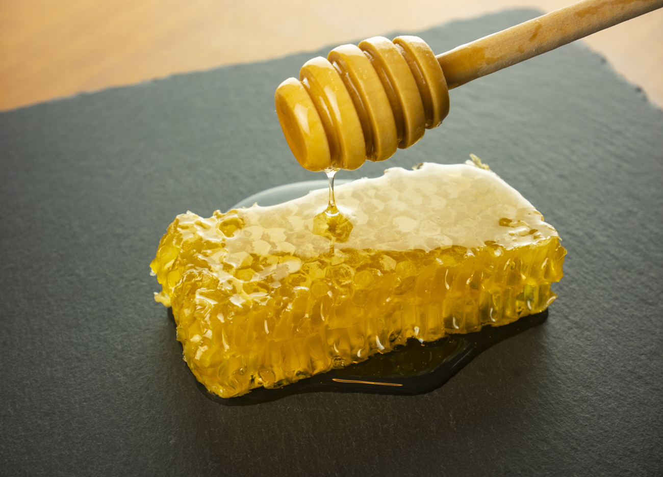 honeycomb with honey dipper on black slate plate still life honey food