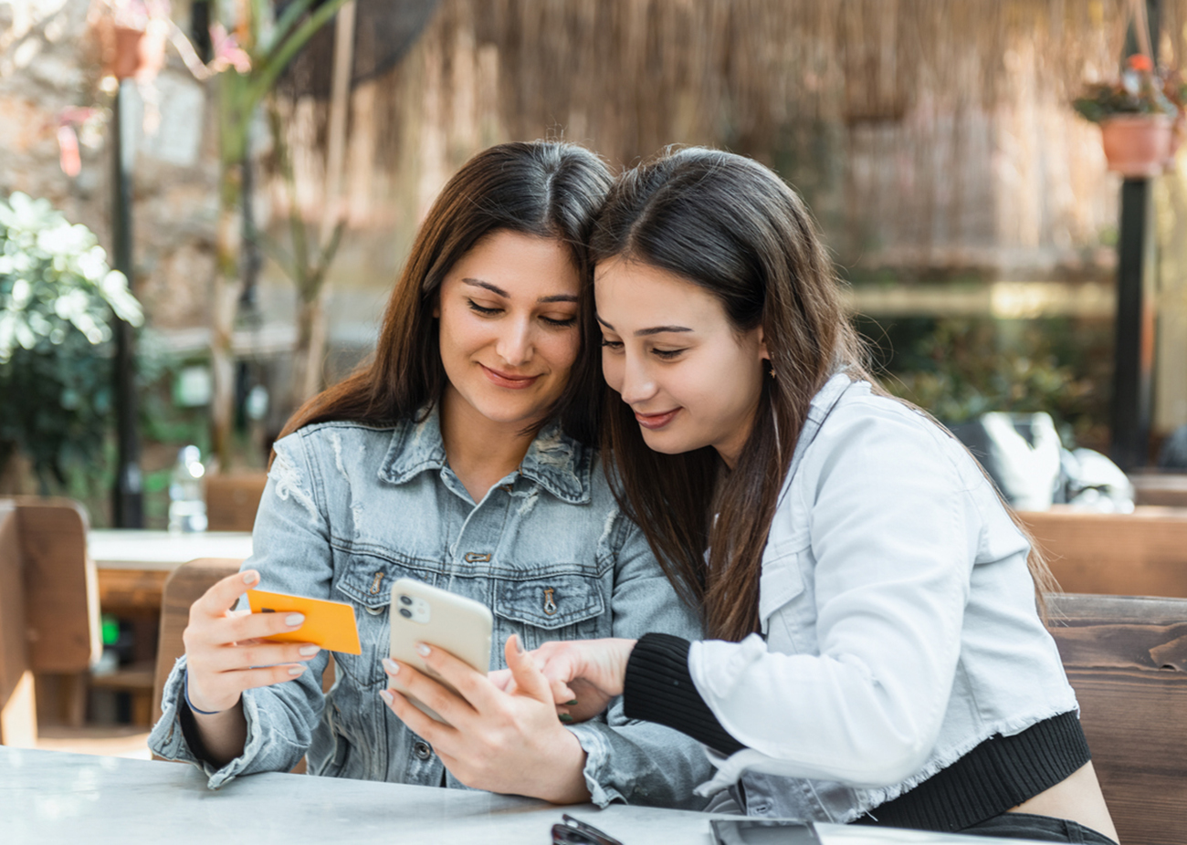 Young two women in a cafe shopping online with credit card. Horizontal composition.