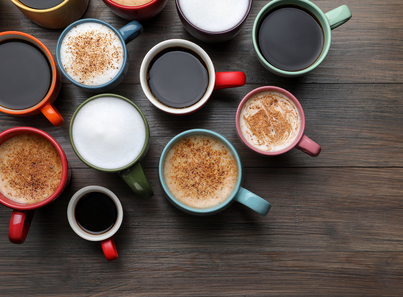 Many different cups with aromatic hot coffee on wooden table, flat lay