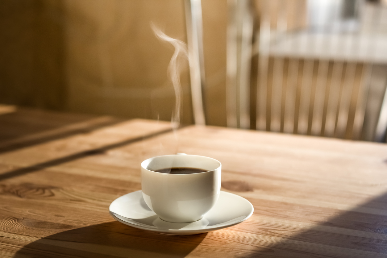 Kitchen interior in natural light, wood table with hot steaming drink on it