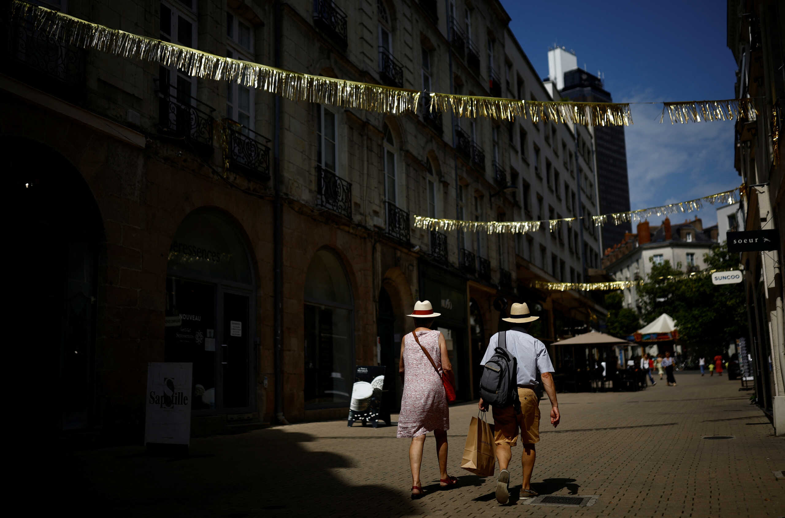 People wearing hats walk in a street during high temperatures in Nantes, France, August 23, 2023. REUTERS