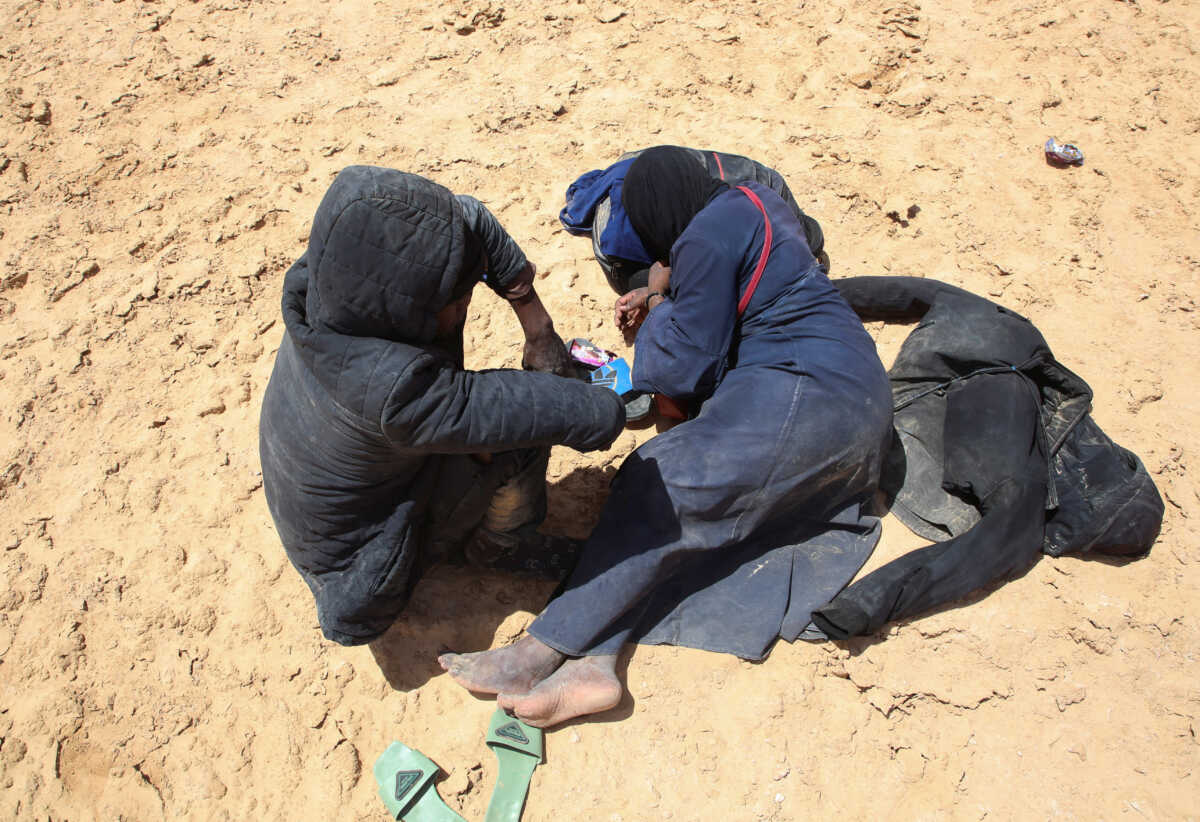 Blessing David, a pregnant 20-year-old woman from Ghana, and her husband rest while they are stranded in the desert on the Libyan-Tunisian border, near Al-Assah, Libya August 5, 2023. REUTERS