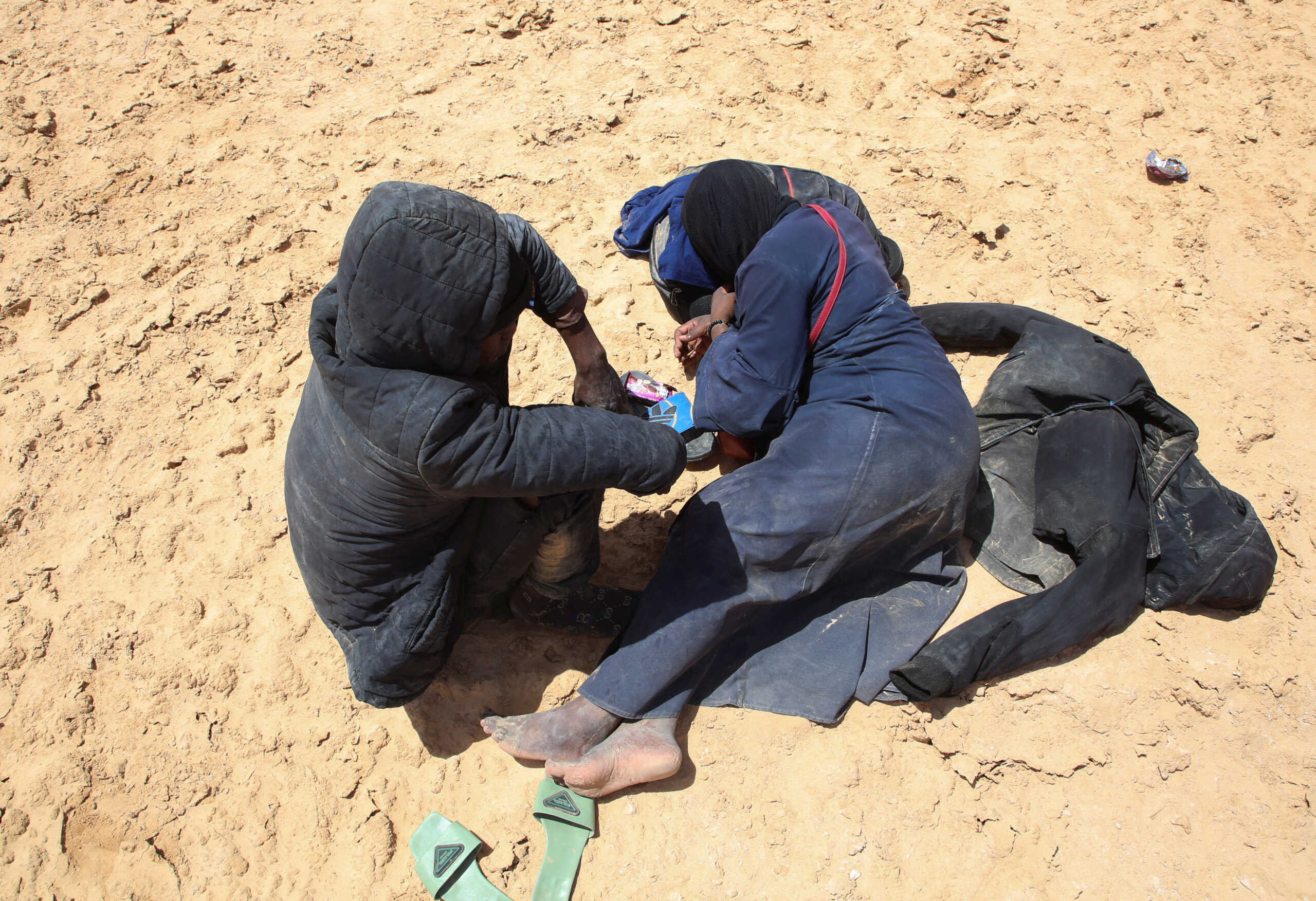 Blessing David, a pregnant 20-year-old woman from Ghana, and her husband rest while they are stranded in the desert on the Libyan-Tunisian border, near Al-Assah, Libya August 5, 2023. REUTERS